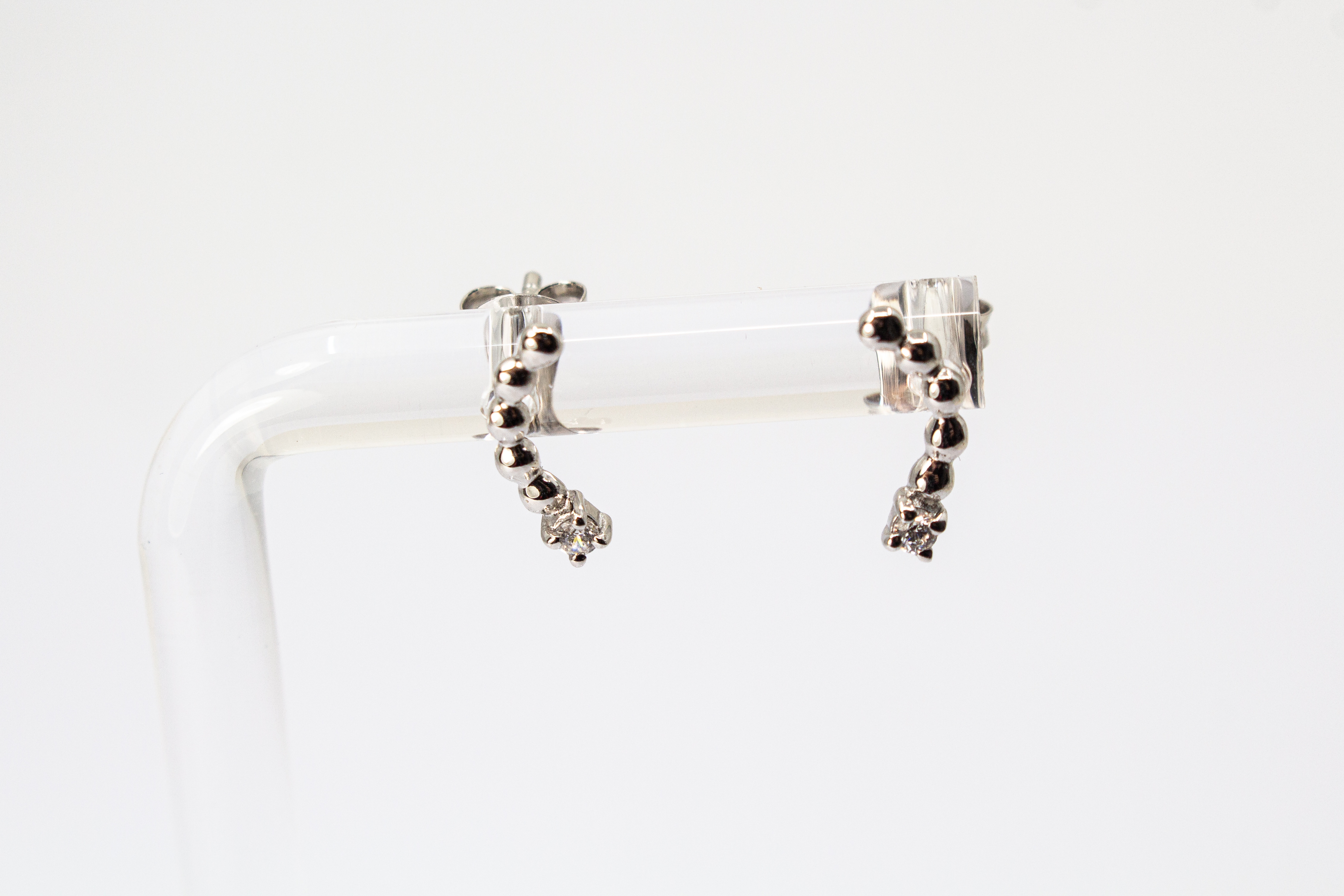 Moderne Ohrstecker aus rhodiniertem 925er Silber mit einem geschwungenen Bogen aus feinen Silberkugeln und funkelnden Zirkoniasteinen im Onlineshop von Goldschmiede Regina Kraus.