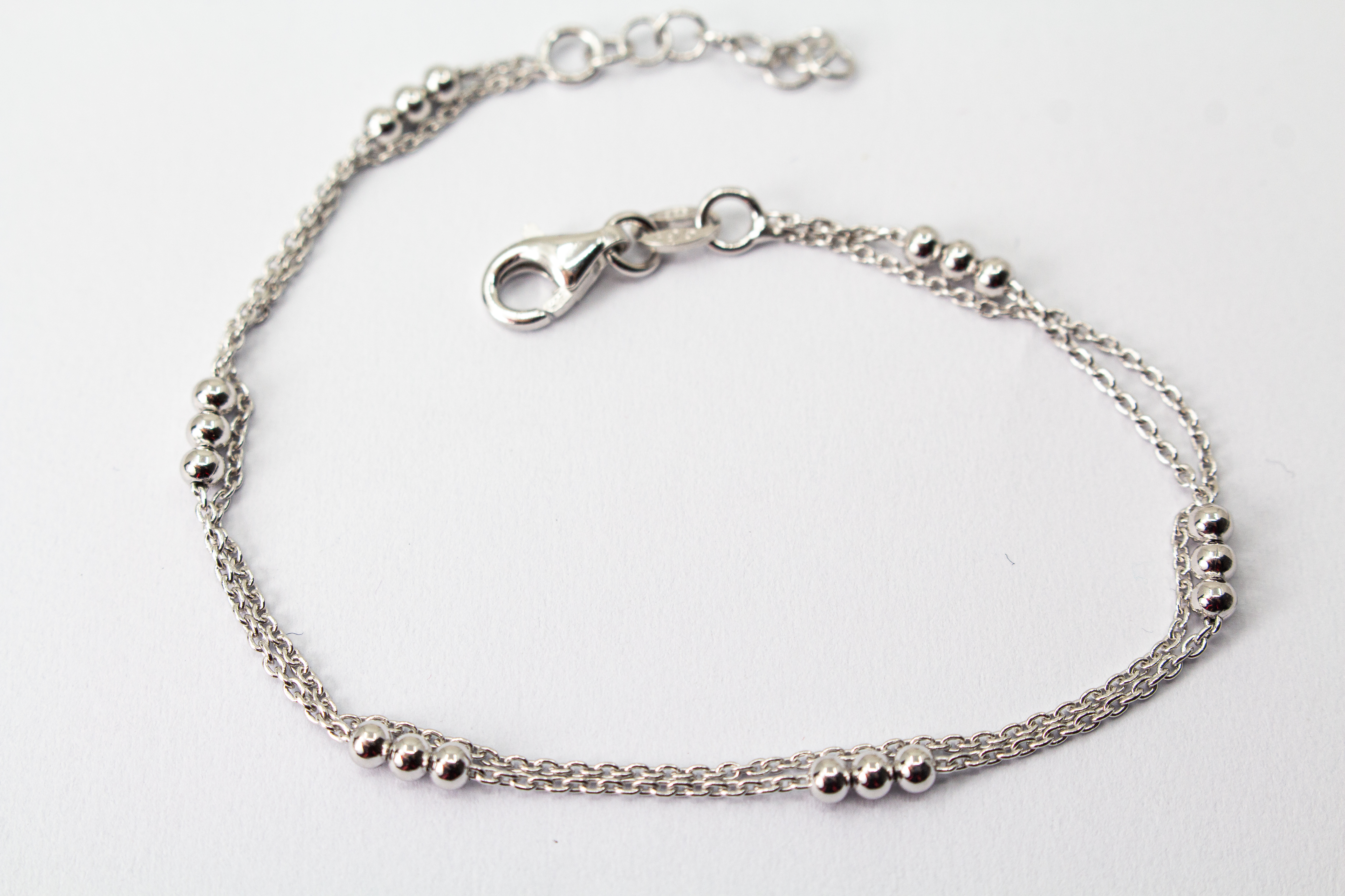 Zweireihiges Armband der Goldschmiede Regina Kraus aus hochwertigem rhodiniertem 925er Silber mit kleinen Silberkugeln in Dreiergruppen auf feinen Ankerketten.