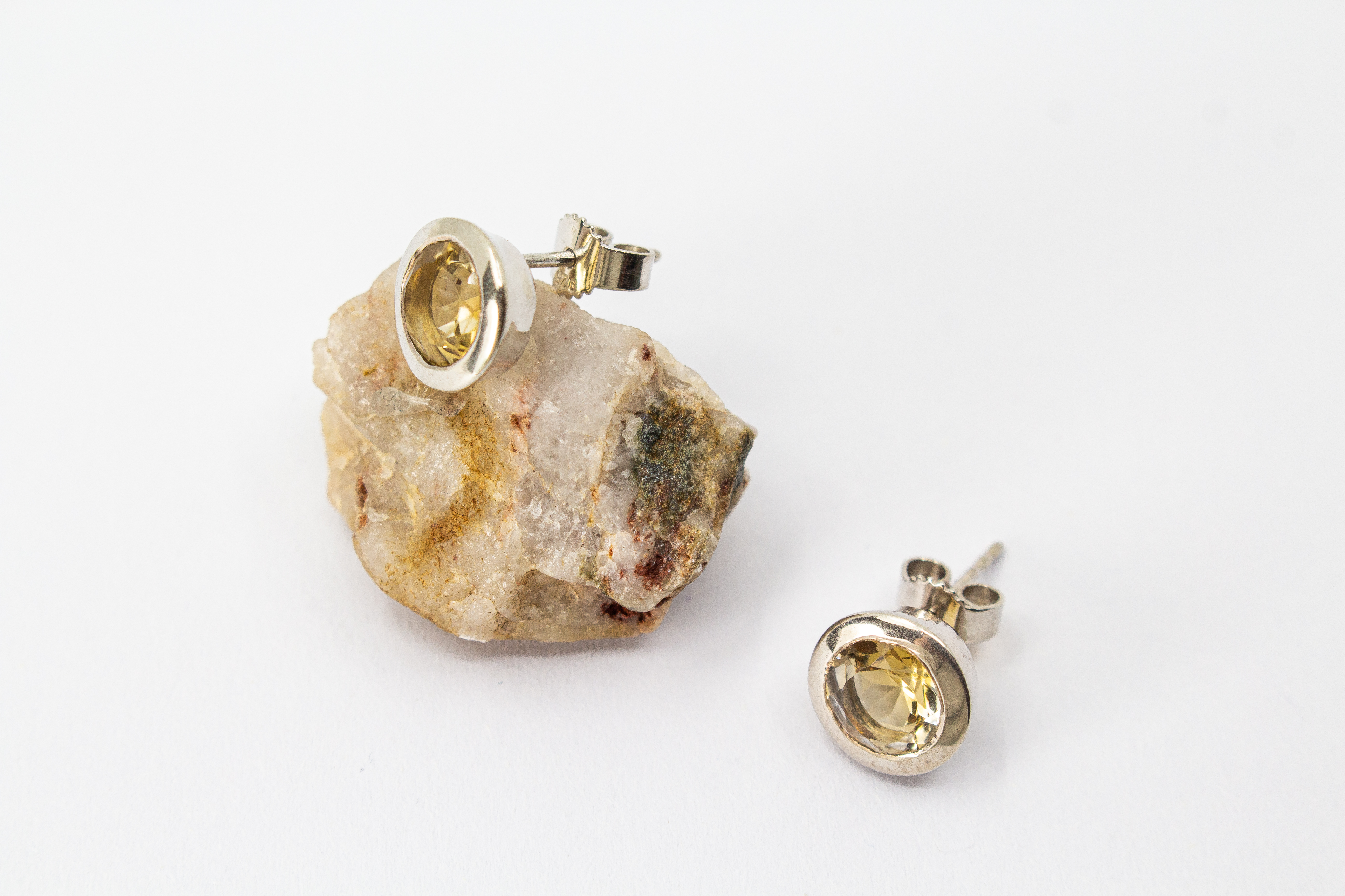 klassische, runde Ohrstecker aus glänzendem 925 Sterling Silber mit einem facettierten, hellgelben Citrin-Edelstein in einer glatten Zargenfassung aus dem Online-Shop der Goldschmiede Regina Kraus.