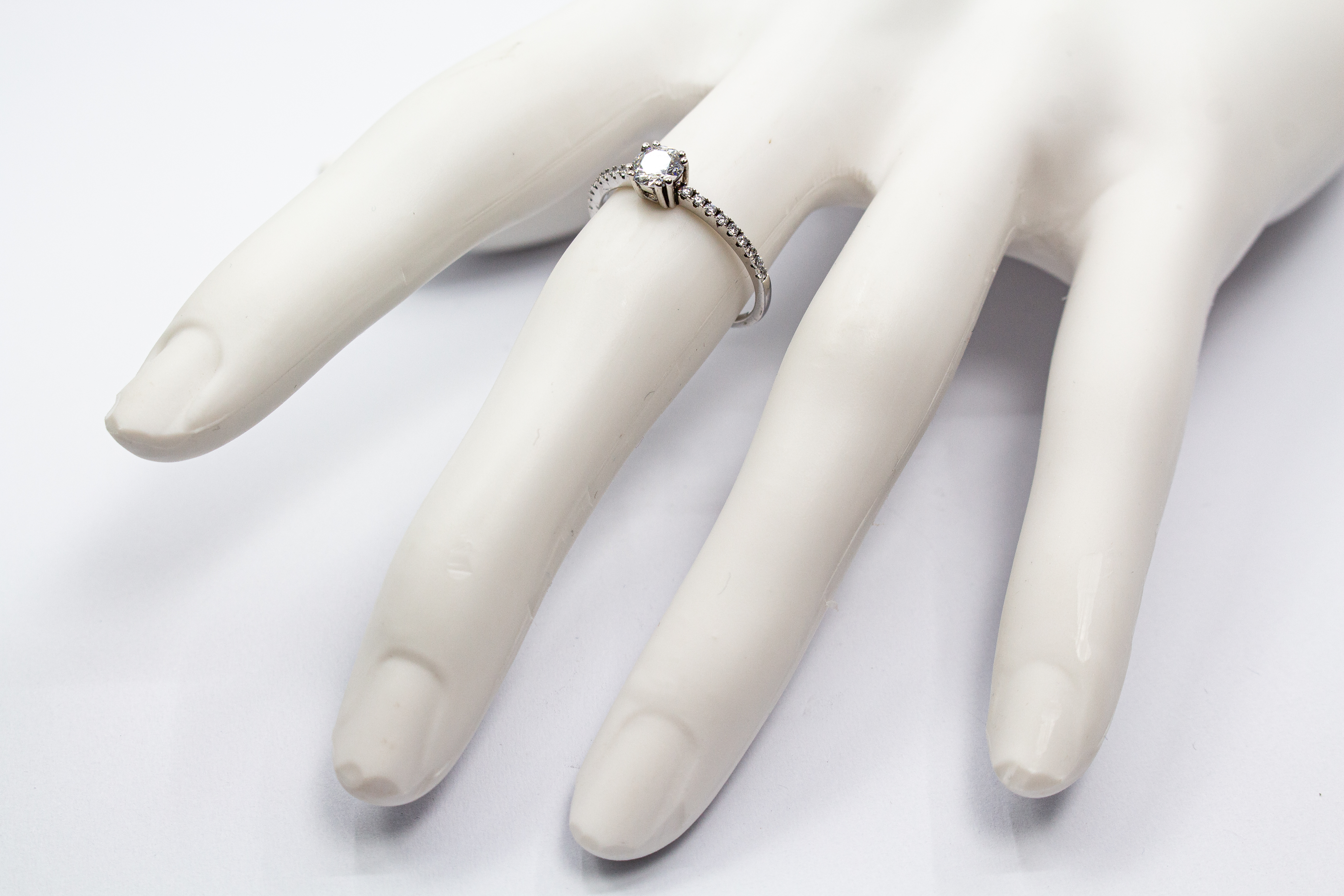 Eleganter Solitärring aus rhodiniertem 925er Silber mit einem großen, in einer Vierer-Krappenfassung gehaltenen Zirkonia und einer mit kleinen Zirkoniasteinen besetzten Ringschiene im Onlineshop von Goldschmiede Regina Kraus.