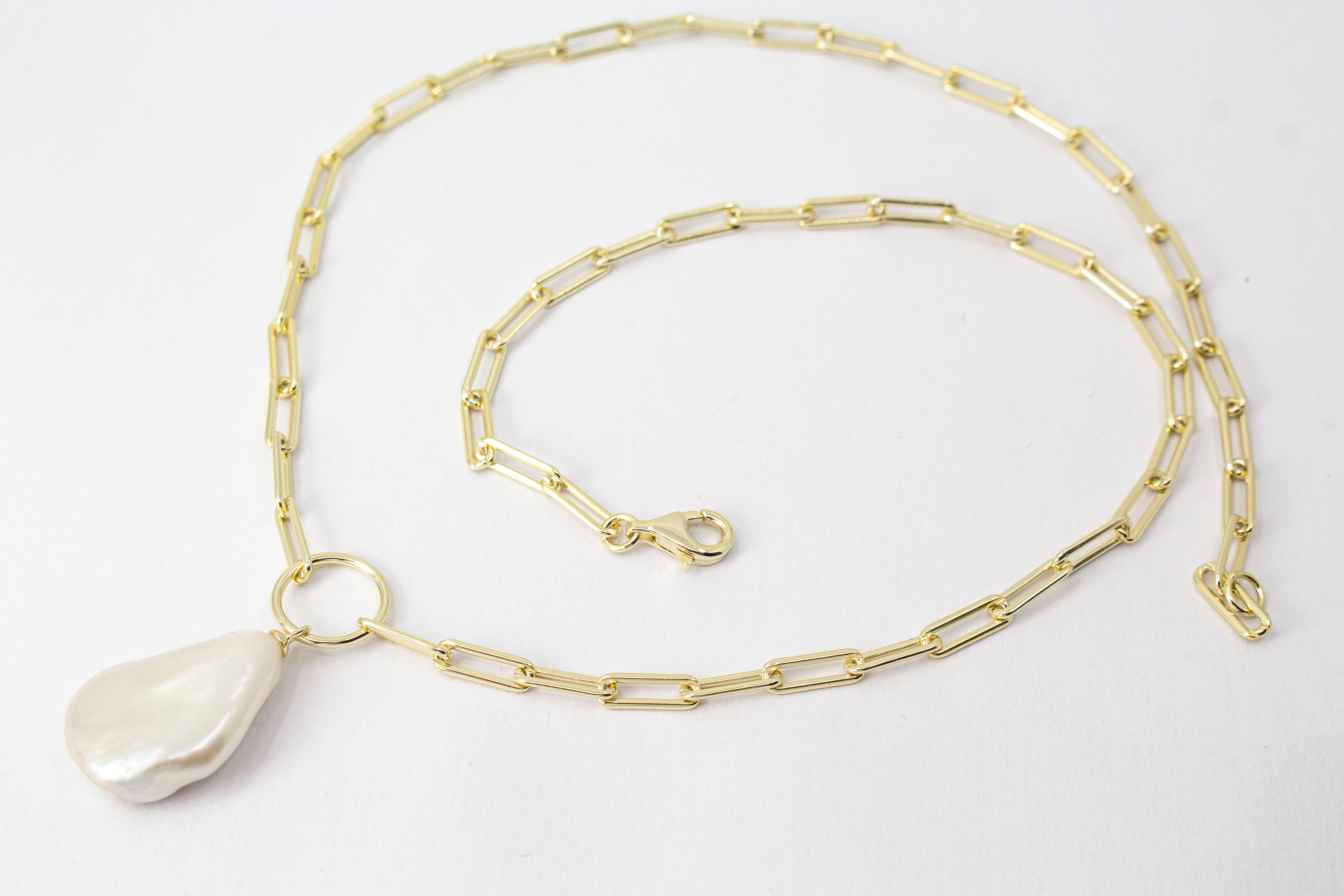 Eine filigrane, hochwertig gelbvergoldete Halskette aus 925er Sterlingsilber von der Goldschmiede Regina Kraus. Als Anhänger dient eine edle, weiße Barock-Zuchtperle mit ihrer typischen, unregelmäßig gewachsenen Form und einem intensiv schimmernden Lüster