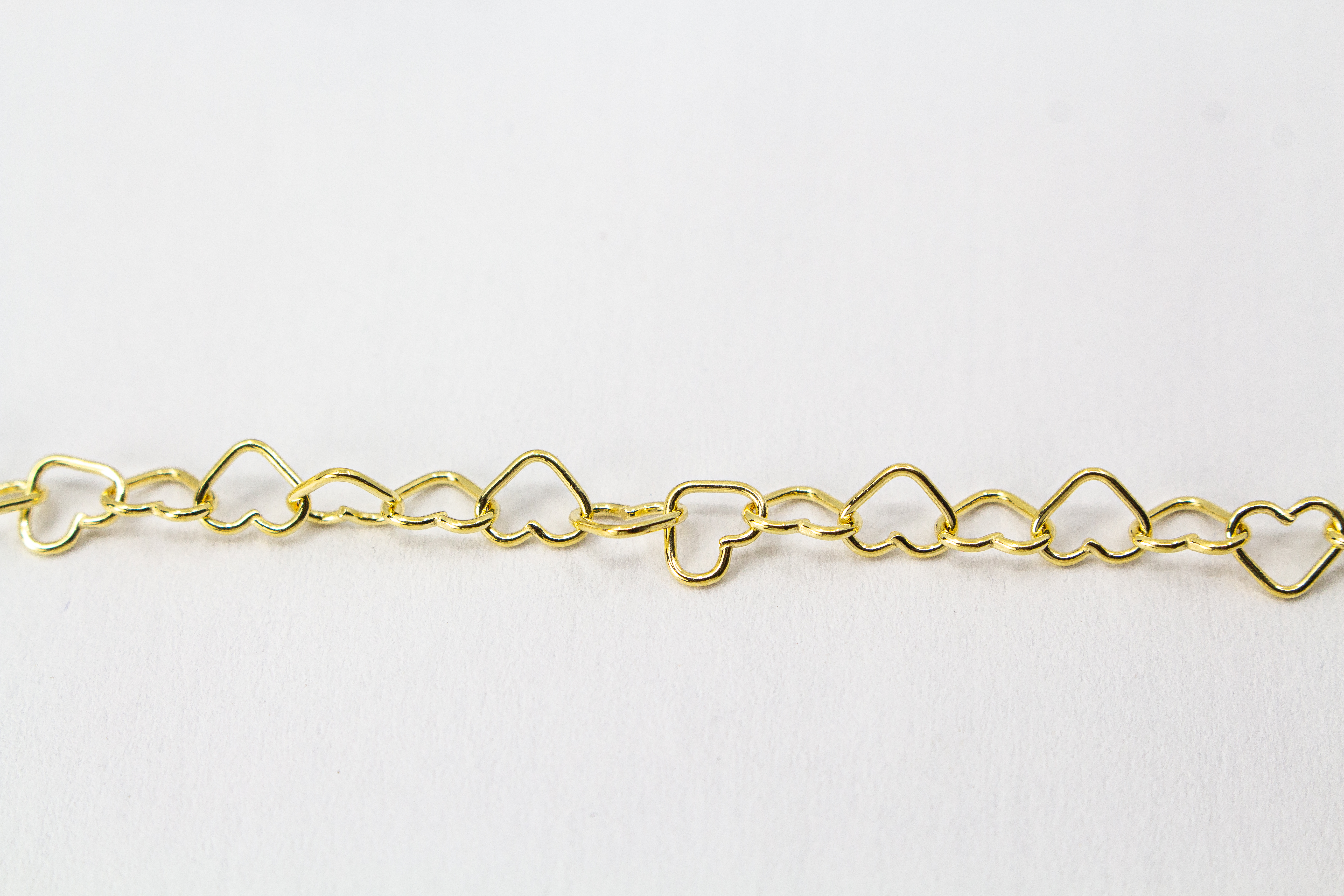 Zartes und hochwertig vergoldetes Fußkettchen aus 925er Sterlingsilber (20 Mikron Vergoldung) bestehend aus einer Kette aneinandergereihte Herz-Glieder mit Karabinerverschluss und Verlängerungskette auf weißem Hintergrund, aus dem Onlineshop der Goldschmi