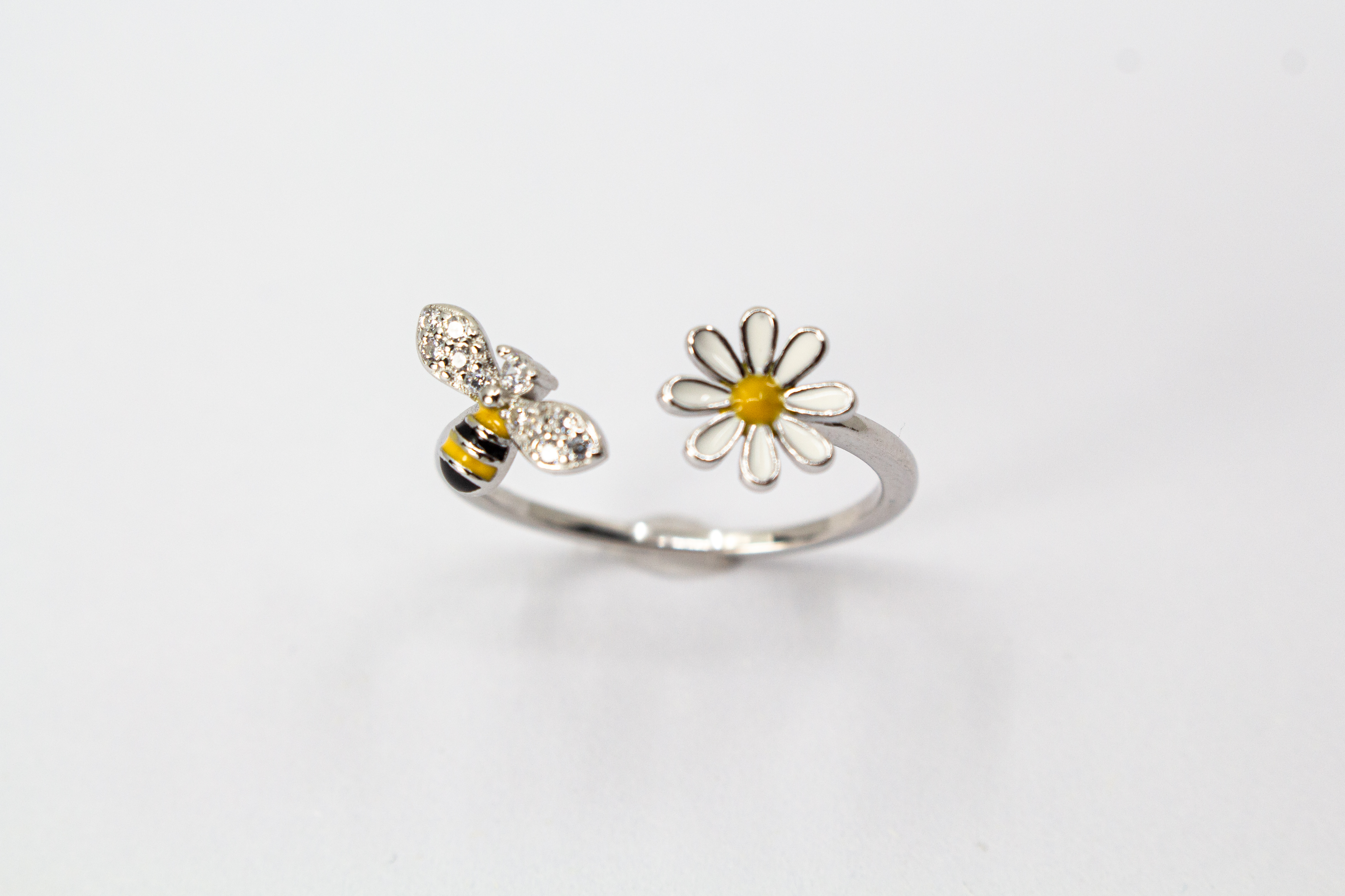 Offener Ring „Blütenbesuch“ aus rhodiniertem 925er Sterlingsilber mit Emaille-Blüte, funkelnder Biene und weißen Zirkonia.