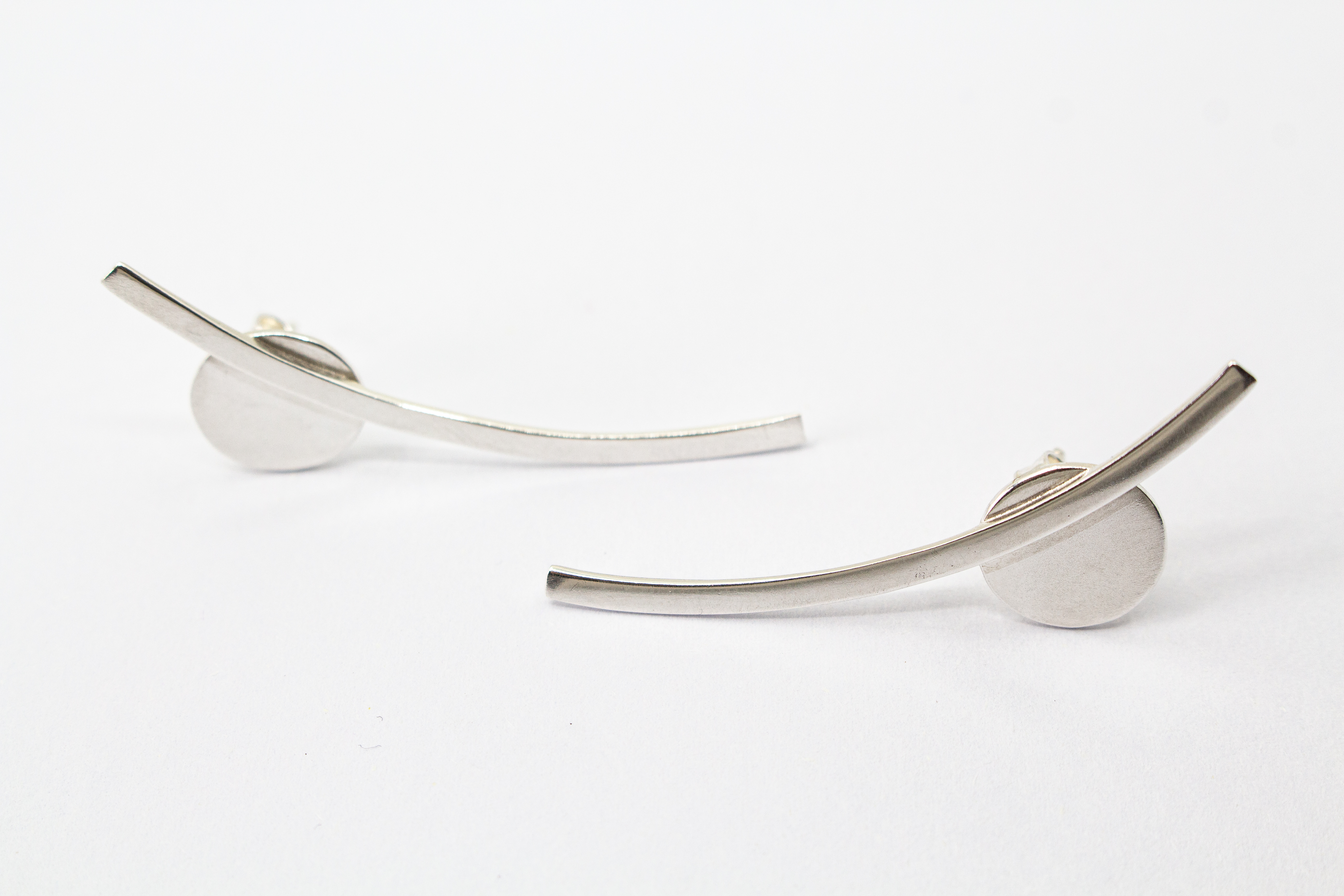 moderne, geometrische Ear Climber Ohrstecker aus glänzendem 925 Sterling Silber mit einer flachen Kreisscheibe und einem geschwungenen Silberstab aus dem Online-Shop der Goldschmiede Regina Kraus.
