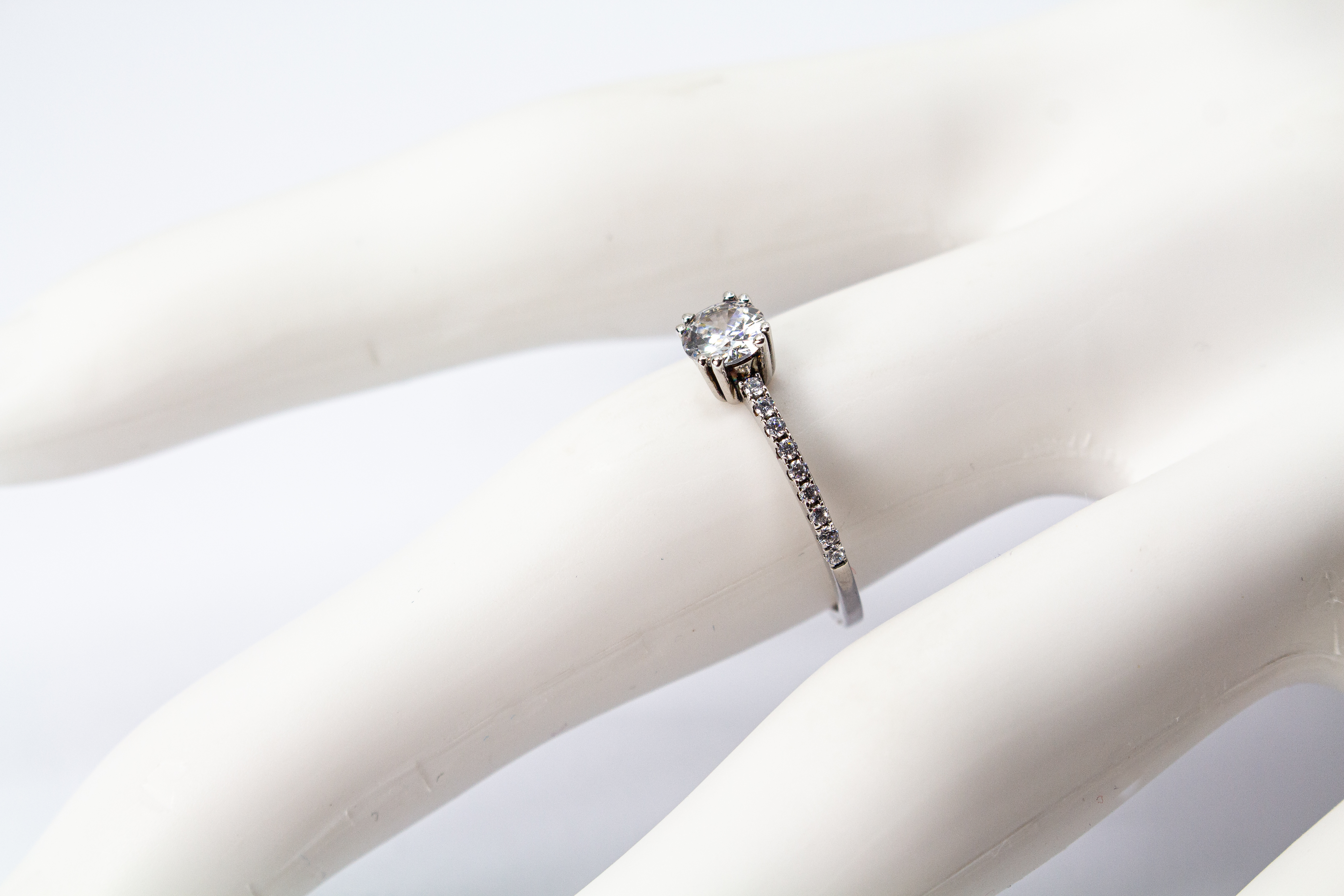 Eleganter Solitärring aus rhodiniertem 925er Silber mit einem großen, in einer Vierer-Krappenfassung gehaltenen Zirkonia und einer mit kleinen Zirkoniasteinen besetzten Ringschiene im Onlineshop von Goldschmiede Regina Kraus.