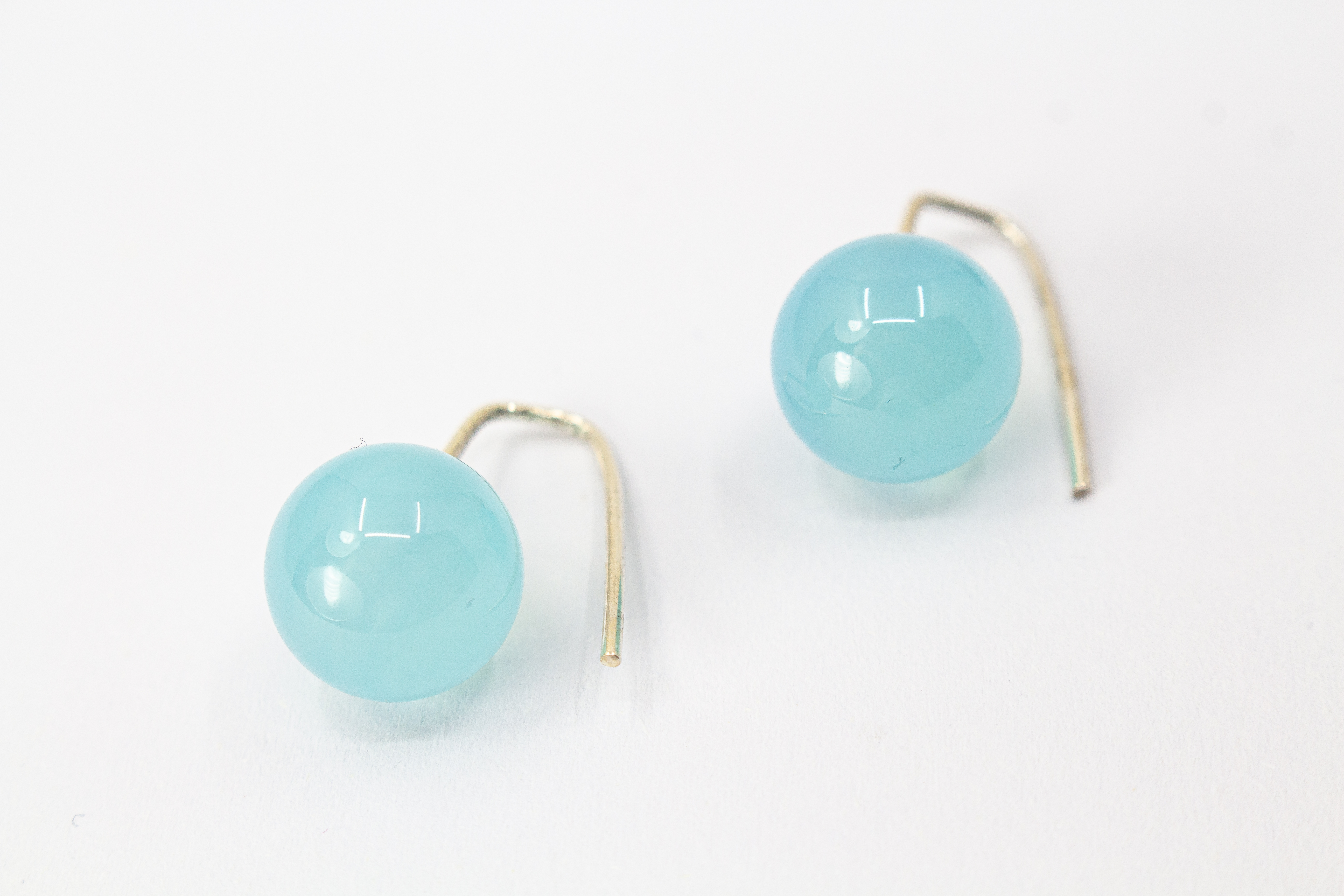 Minimalistische Ohrhänger aus feinen 925 Sterling Silberbügeln mit je einer glatten, hellblauen Chalcedon-Edelsteinkugel aus dem Online-Shop der Goldschmiede Regina Kraus