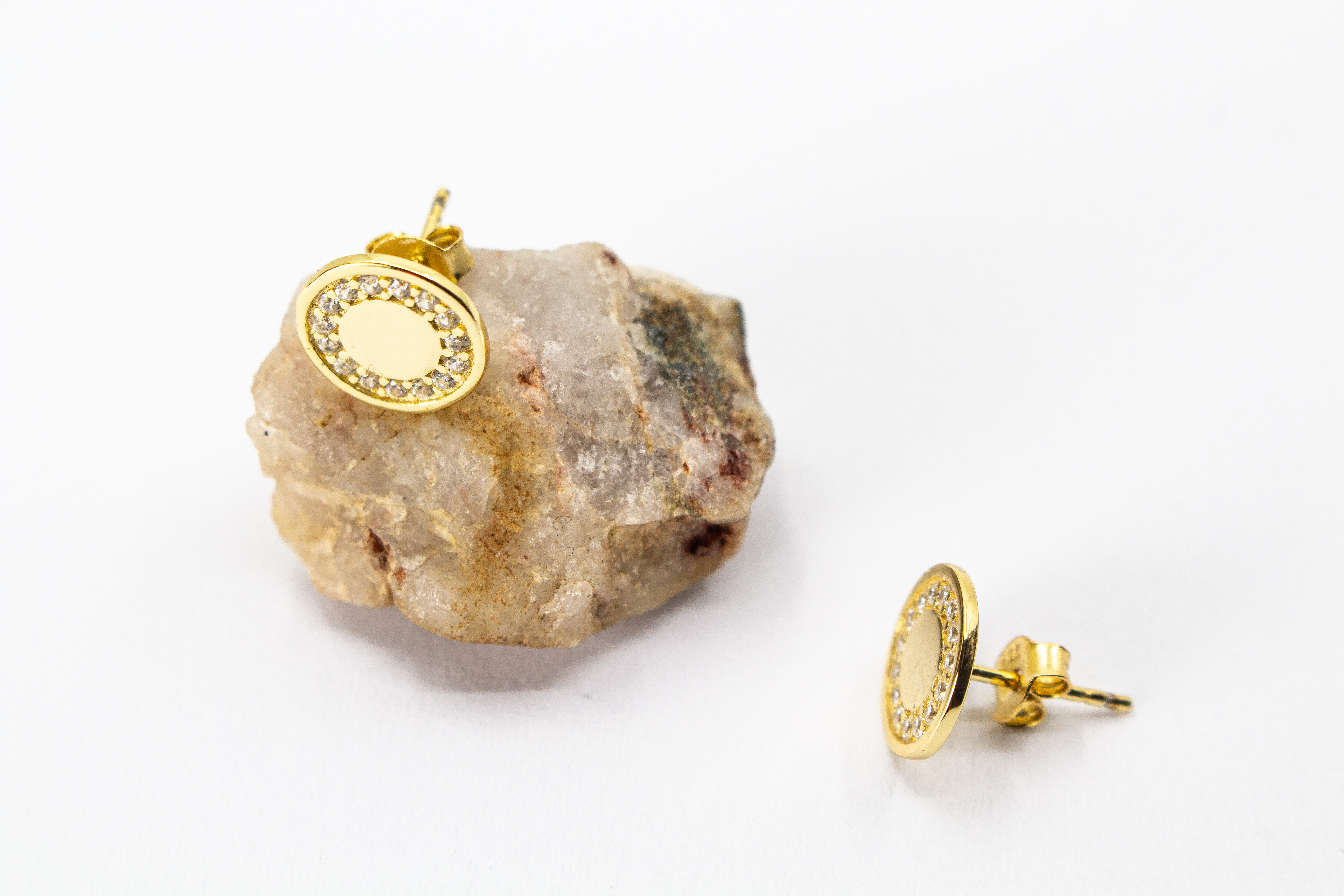 Runde, vergoldete Ohrstecker aus 925er Silber mit einer glatten Innenfläche und einem äußeren Kranz aus funkelnden Zirkoniasteinen im Onlineshop von Goldschmiede Regina Kraus.