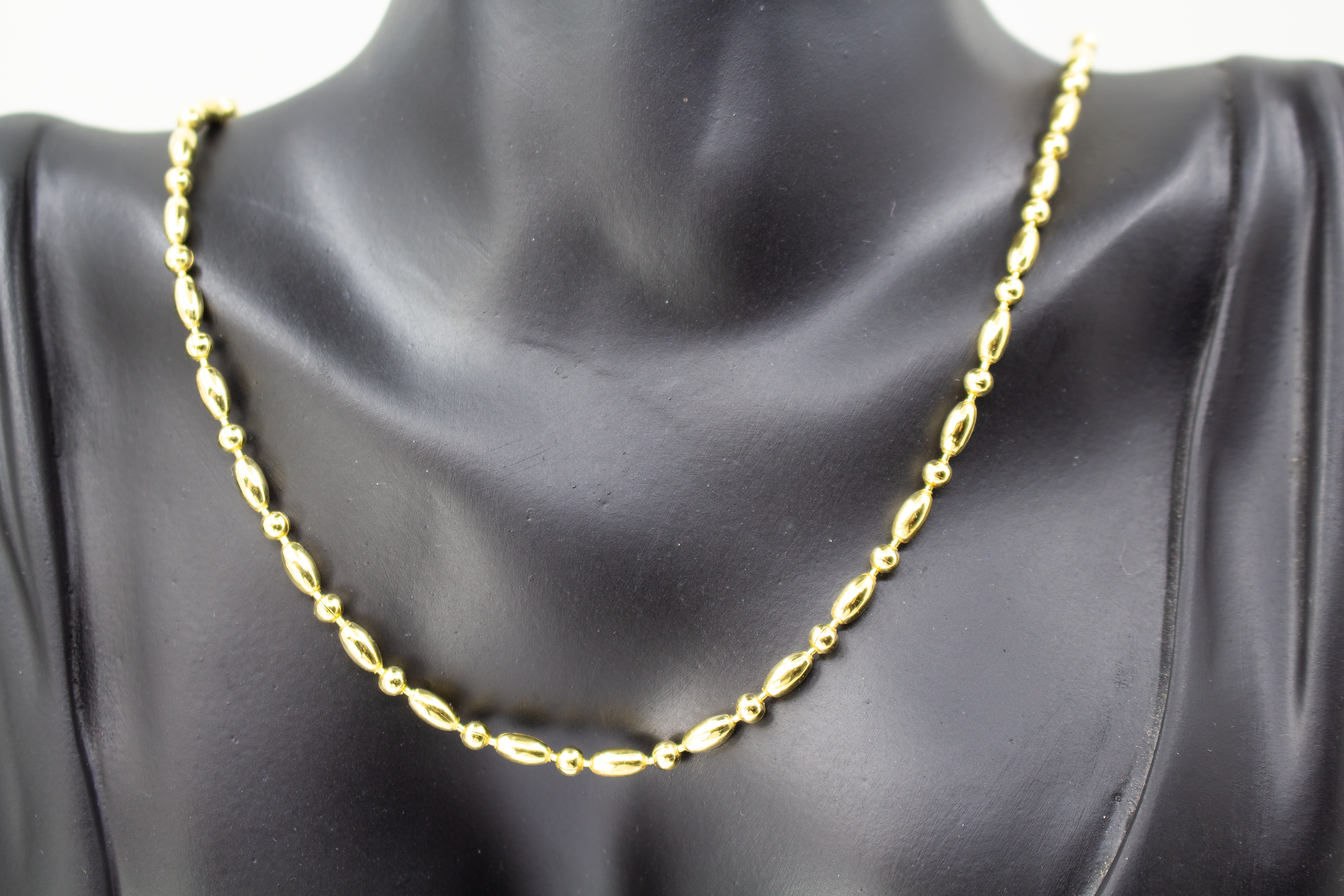 Elegantes, hochwertig vergoldetes Collier aus 925er Sterlingsilber mit einer 20 Mikron Vergoldung, gestaltet in einem rhythmischen Wechsel aus polierten Oliven- und Kugel-Elementen auf hellem Hintergrund, aus dem Schmuck-Onlineshop der Goldschmiede Regina