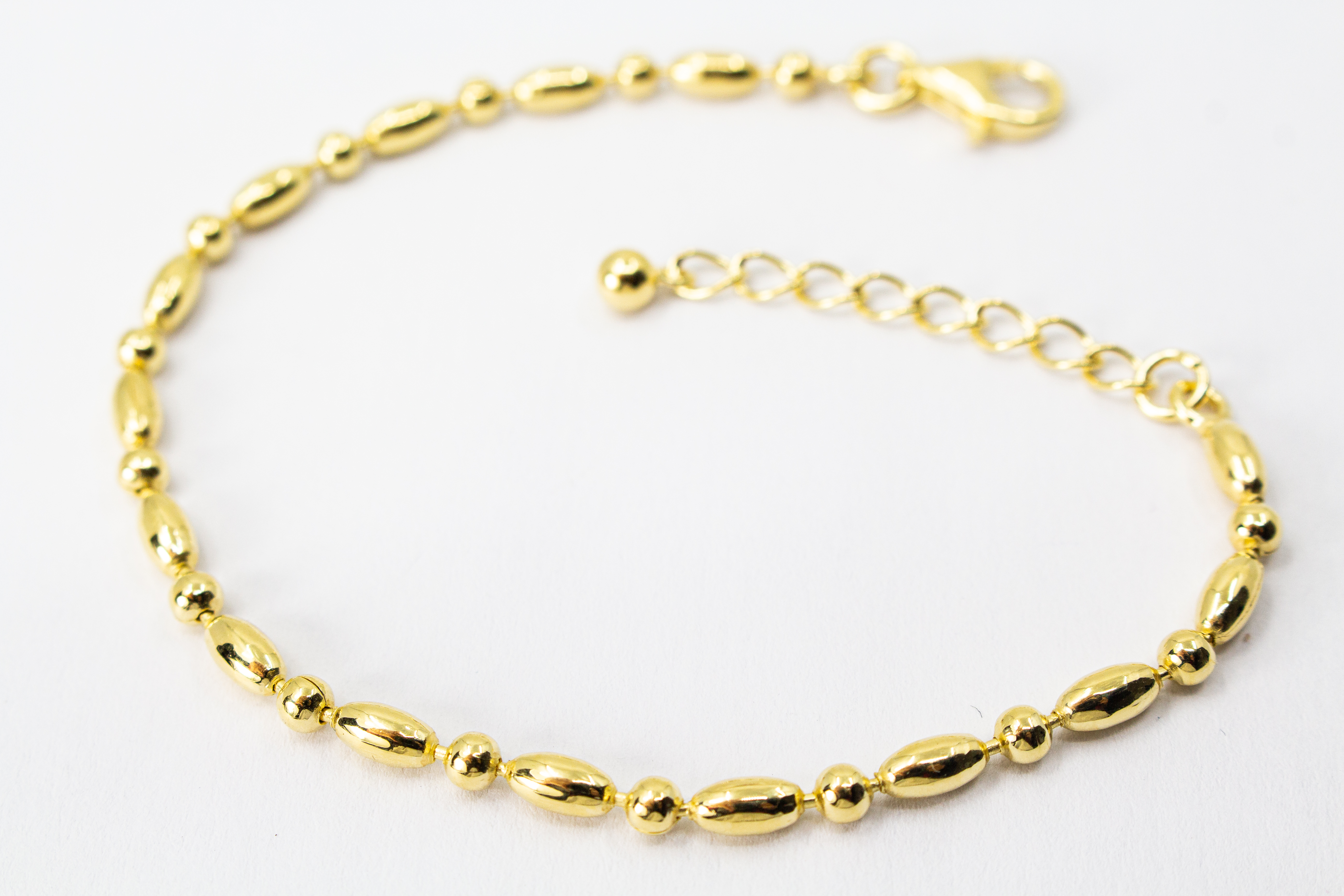 Filigranes, hochwertig vergoldetes Silberarmband (925er Silber, 20 Mikron Vergoldung) mit einem wechselnden Muster aus glänzenden Oliven- und Kugel-Elementen sowie Karabinerverschluss, erhältlich im Onlineshop der Goldschmiede Regina Kraus.