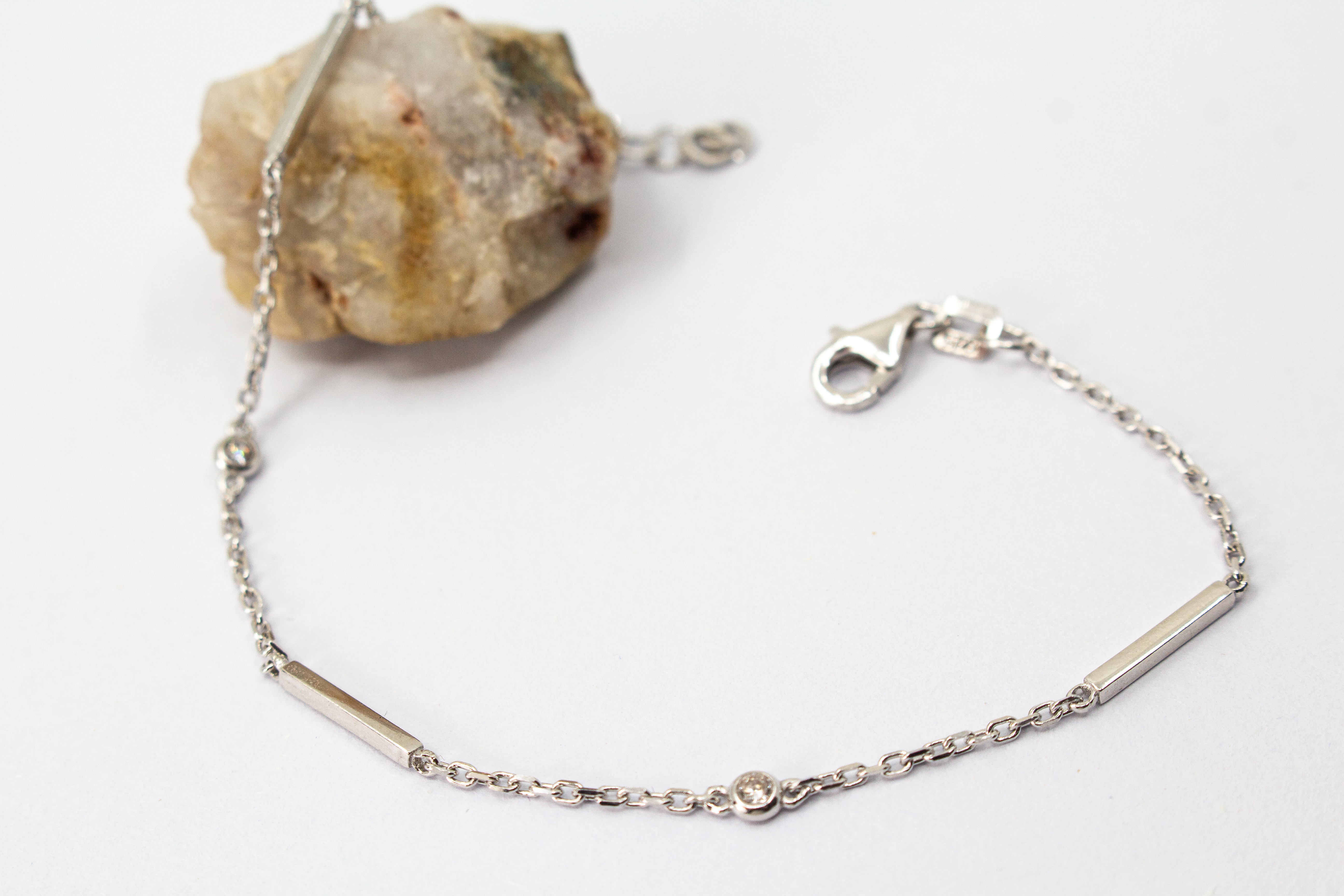 Filigranes, rhodiniertes Damen-Armkettchen aus 925 Sterling Silber mit kleinen, rund gefassten Zirkonia-Steinen und glatten, minimalistischen Stäbchen-Elementen aus dem Online-Shop der Goldschmiede Regina Kraus.