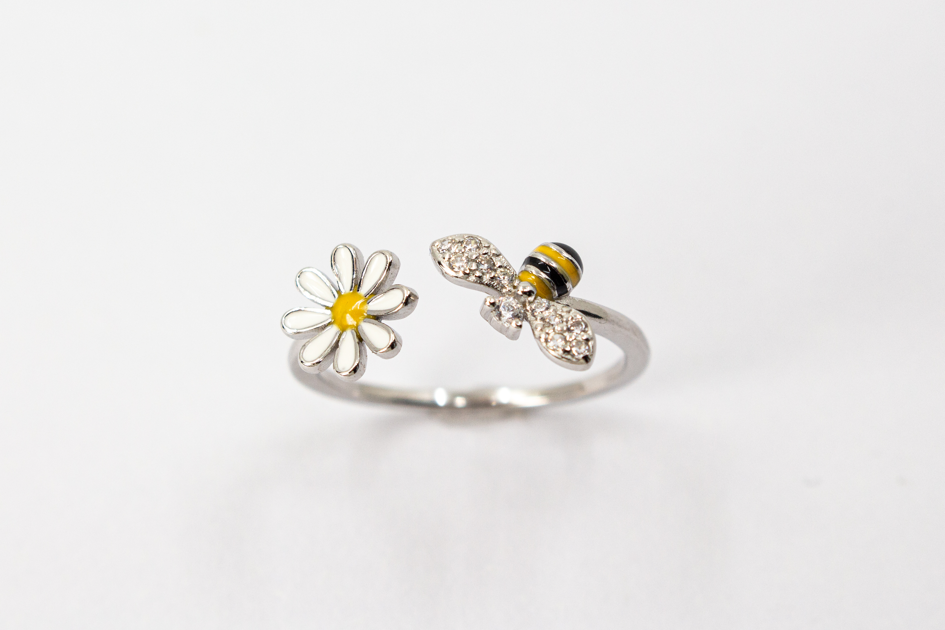 Offener Ring „Blütenbesuch“ aus rhodiniertem 925er Sterlingsilber mit Emaille-Blüte, funkelnder Biene und weißen Zirkonia.