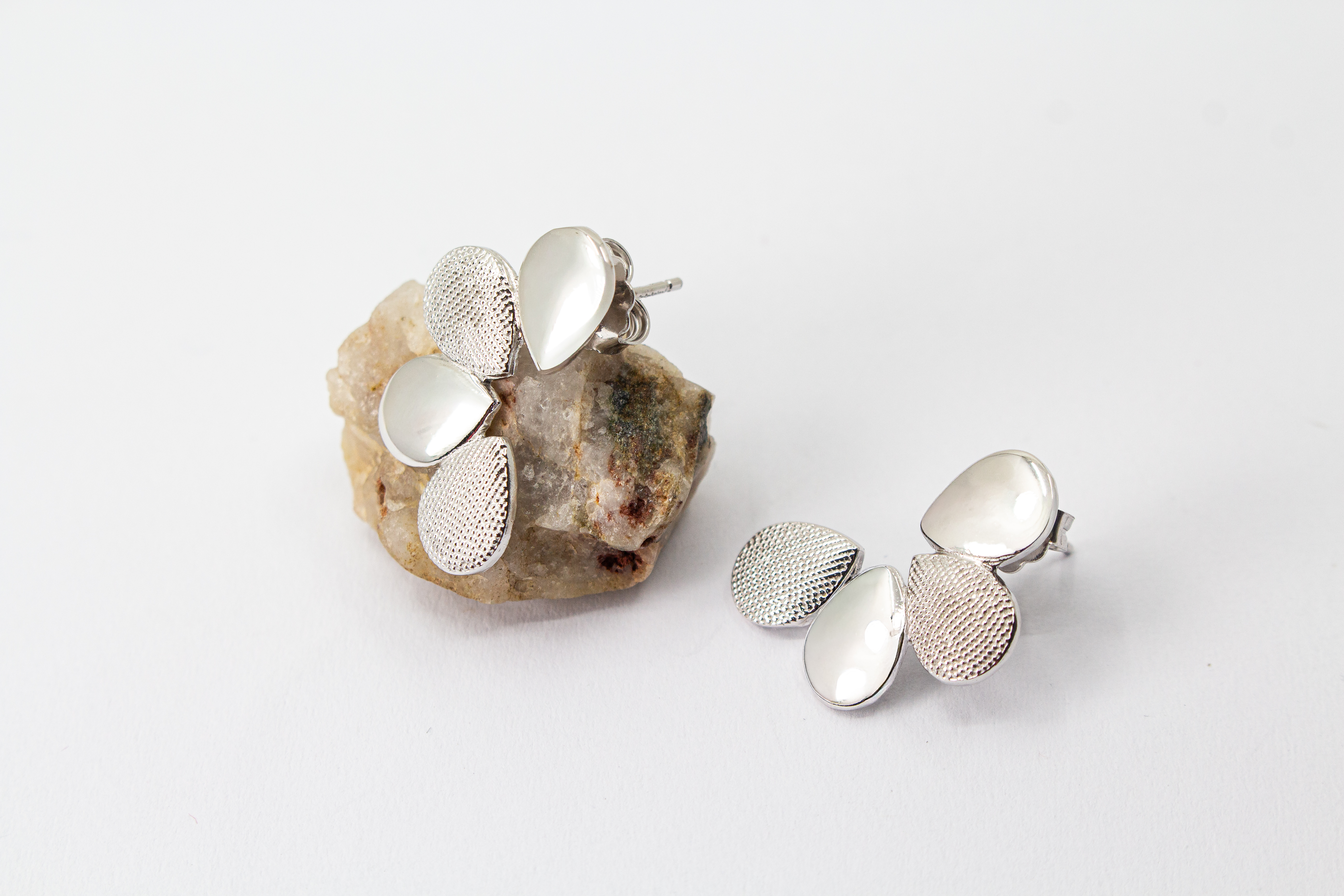 Moderne Ohrstecker der Cosmic Drop Serie von Diva Gioielli aus rhodiniertem 925 Silber. Die Ohrringe zeigen eine fächerförmige Anordnung von glatten und punktförmig strukturierten Tropfen