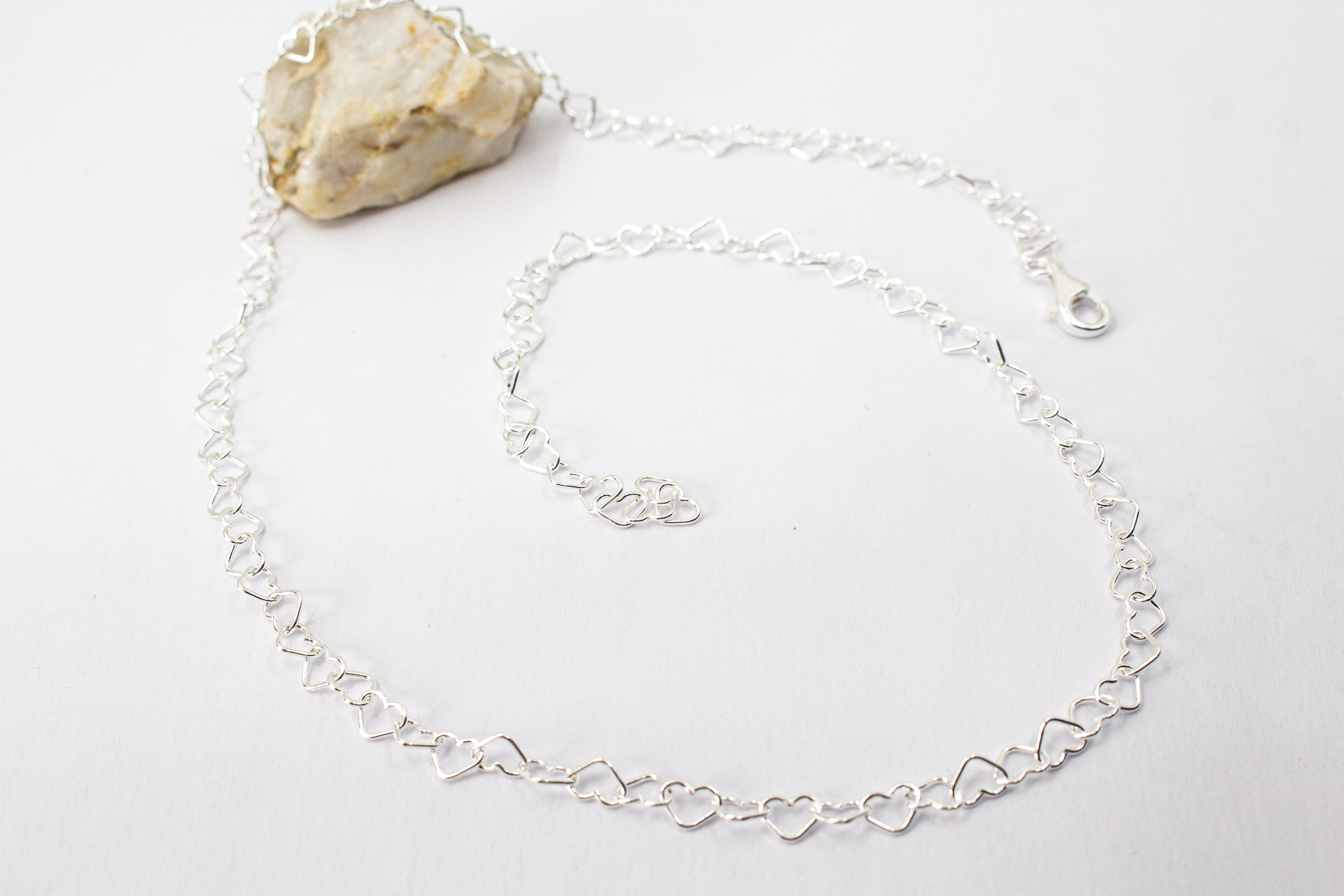 Zarte Halskette „Herz an Herz“ aus 925er Sterlingsilber, gefertigt aus einer Reihe kleiner, miteinander verbundener offener Herzen aus dem Onlineshop der Goldschmiede Regina Kraus.
