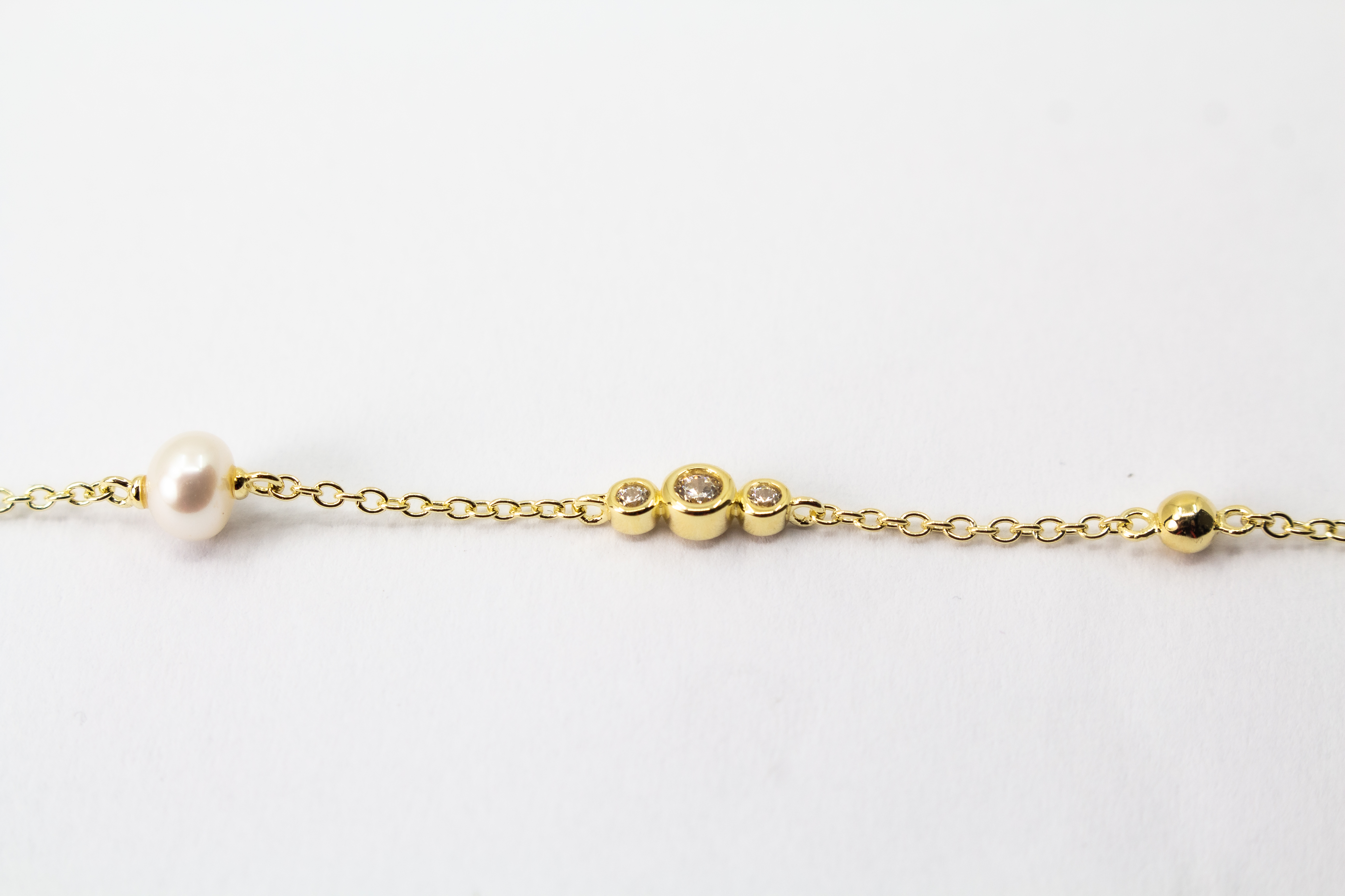 Edles Armband der Goldschmiede Regina Kraus aus vergoldetem 925er Silber mit einer zentralen Süßwasserperle, flankiert von funkelnden Zirkonia-Elementen und kleinen Goldkugeln
