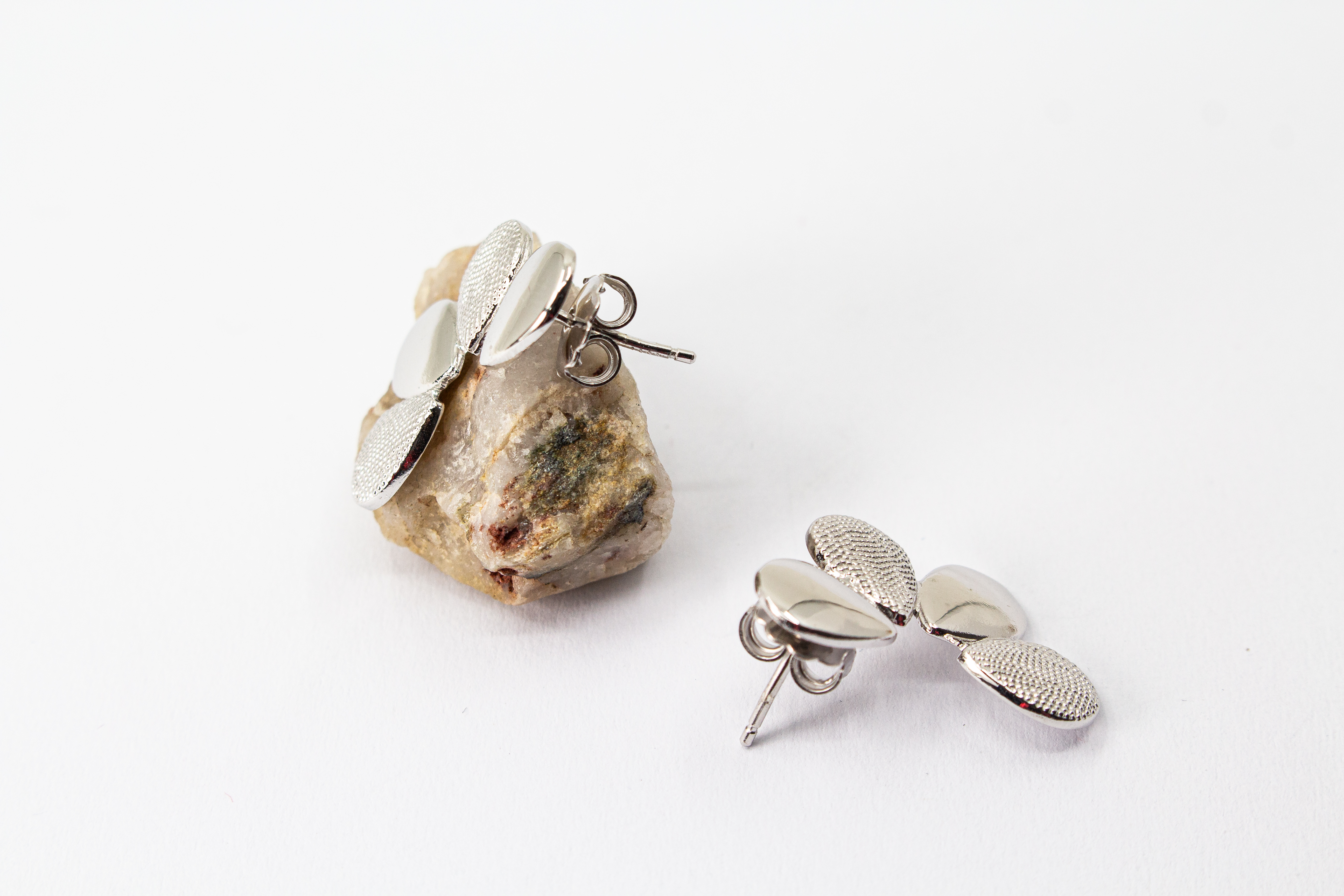 Moderne Ohrstecker der Cosmic Drop Serie von Diva Gioielli aus rhodiniertem 925 Silber. Die Ohrringe zeigen eine fächerförmige Anordnung von glatten und punktförmig strukturierten Tropfen
