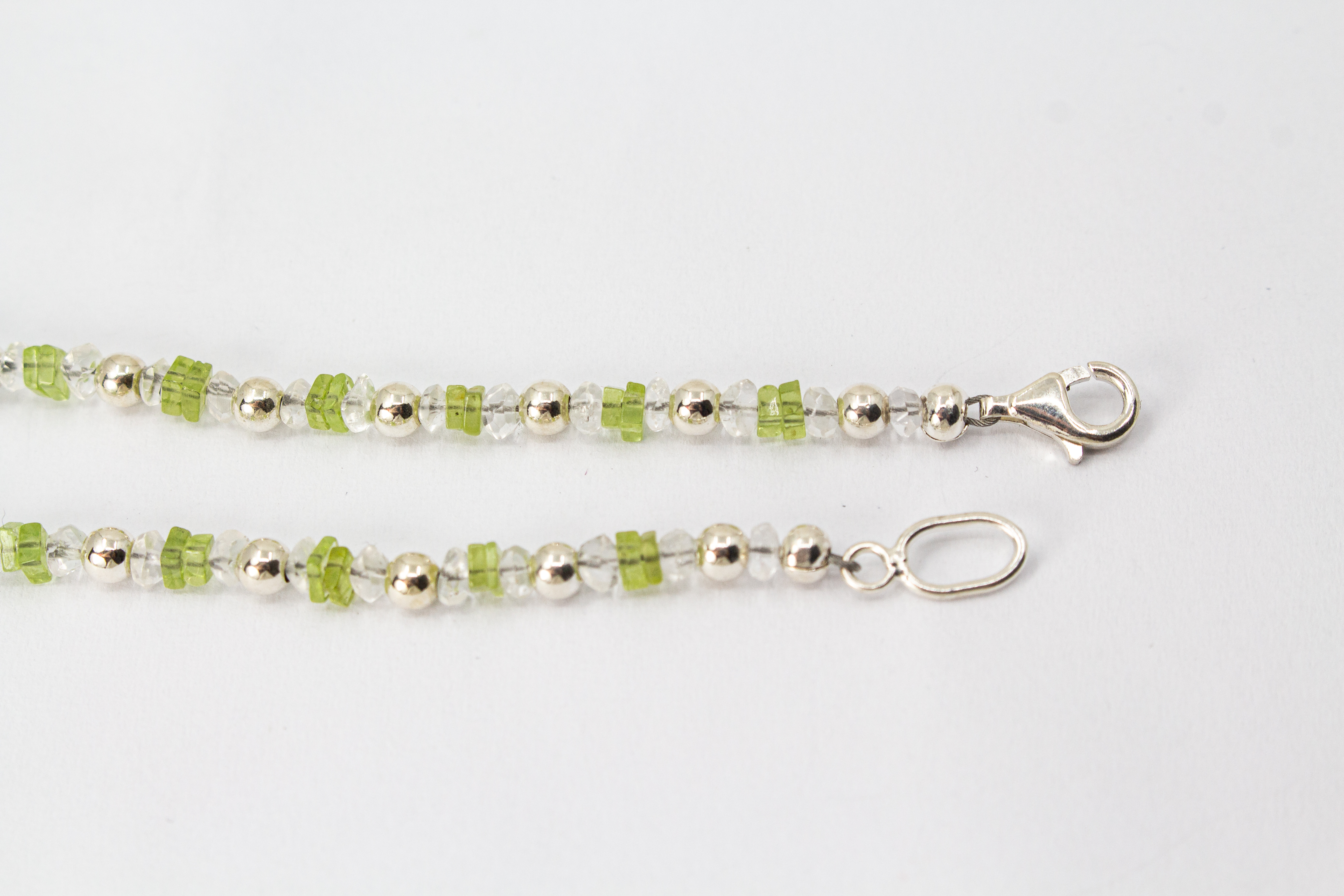Filigrane Edelsteinhalskette aus hellgrünen Peridot-Splittern, klaren Bergkristall-Elementen und glänzenden 925 Sterling Silberkugeln aus dem Online-Shop der Goldschmiede Regina Kraus