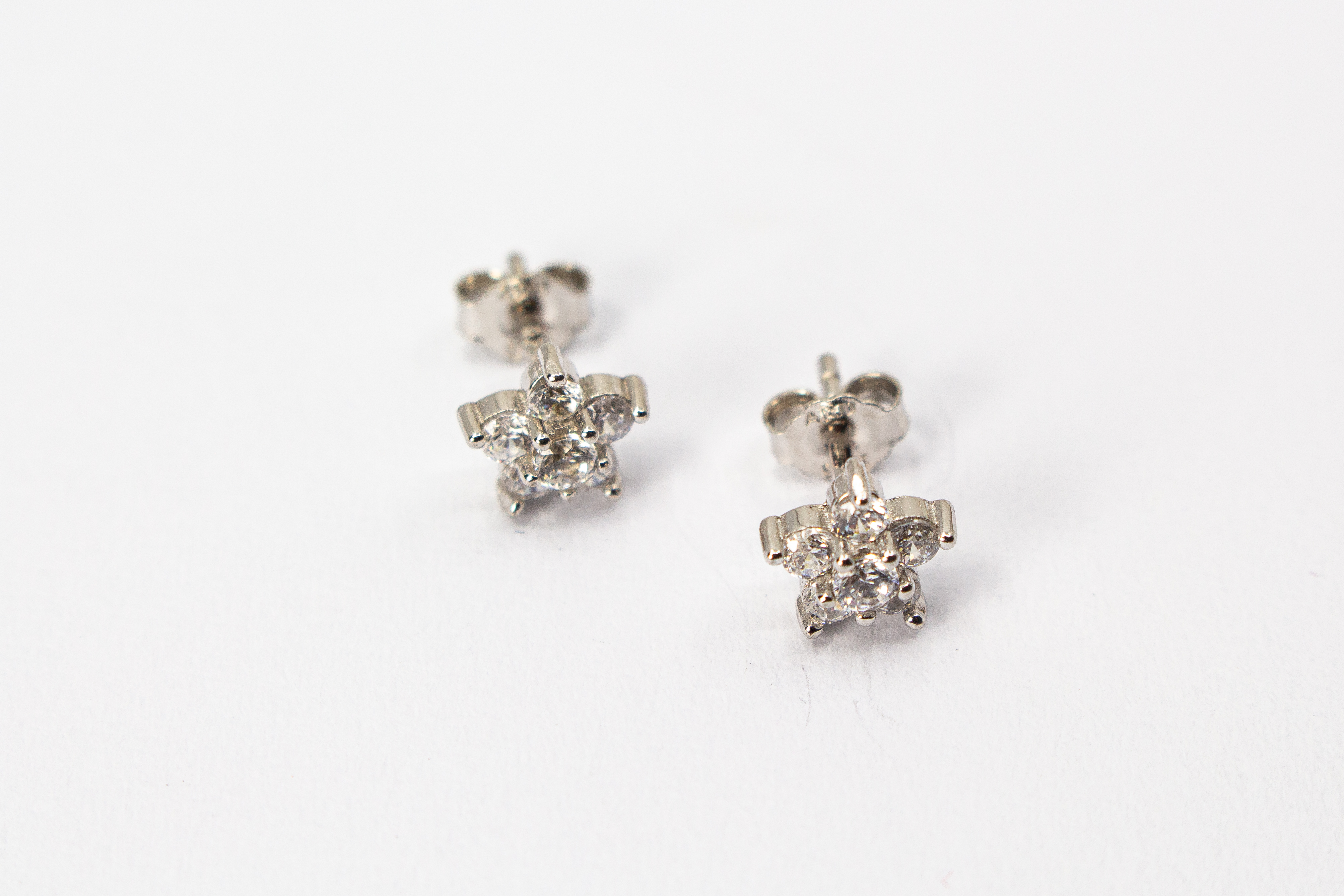 Filigrane Blumen-Ohrstecker aus rhodiniertem 925er Silber in Form einer kleinen Blüte mit funkelndem Zirkonia-Besatz im Onlineshop von Goldschmiede Regina Kraus.