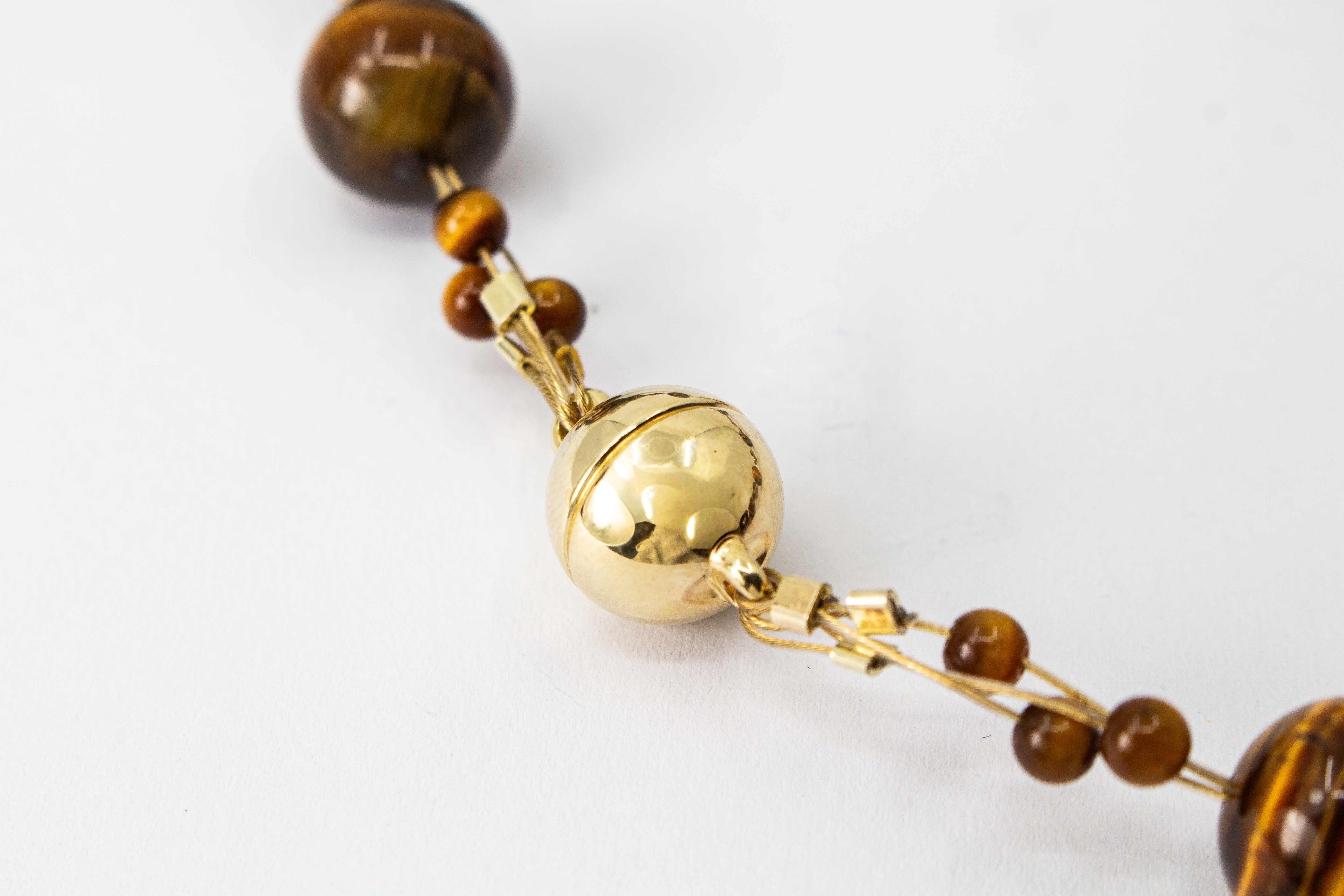 Eine handgefertigte Edelsteinkette der Goldschmiede Regina Kraus aus runden, braungoldenen Tigerauge-Perlen