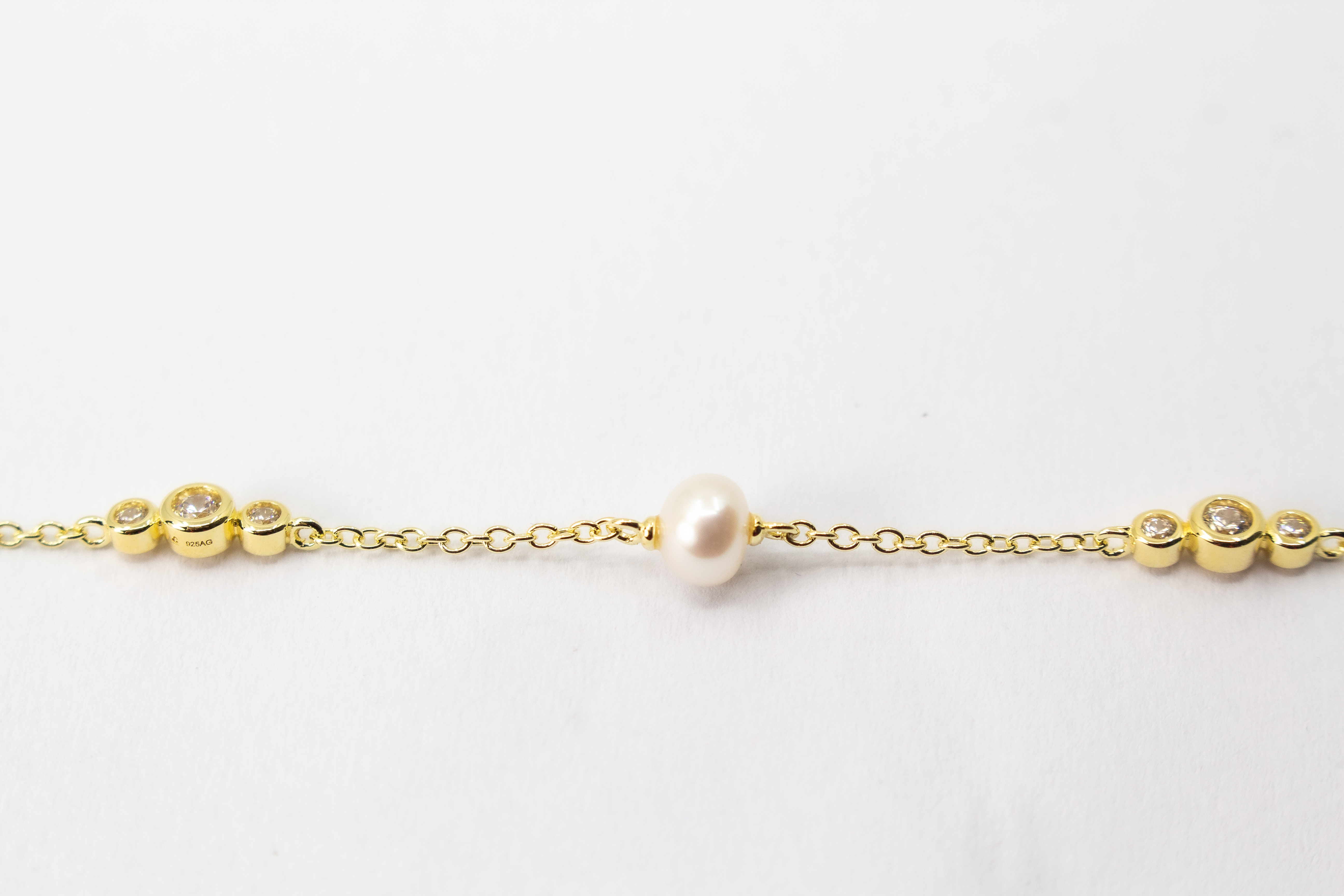 Edles Armband der Goldschmiede Regina Kraus aus vergoldetem 925er Silber mit einer zentralen Süßwasserperle, flankiert von funkelnden Zirkonia-Elementen und kleinen Goldkugeln