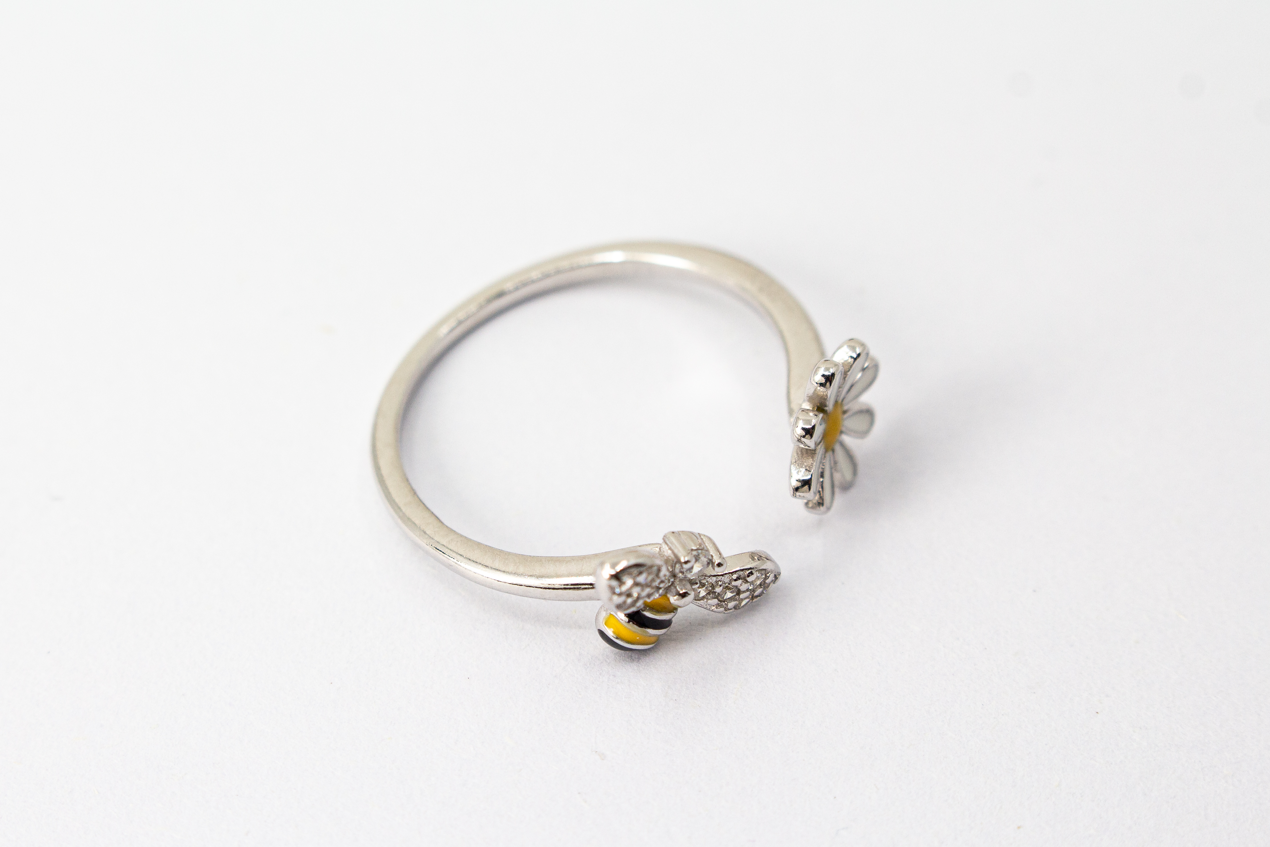 Offener Ring „Blütenbesuch“ aus rhodiniertem 925er Sterlingsilber mit Emaille-Blüte, funkelnder Biene und weißen Zirkonia.