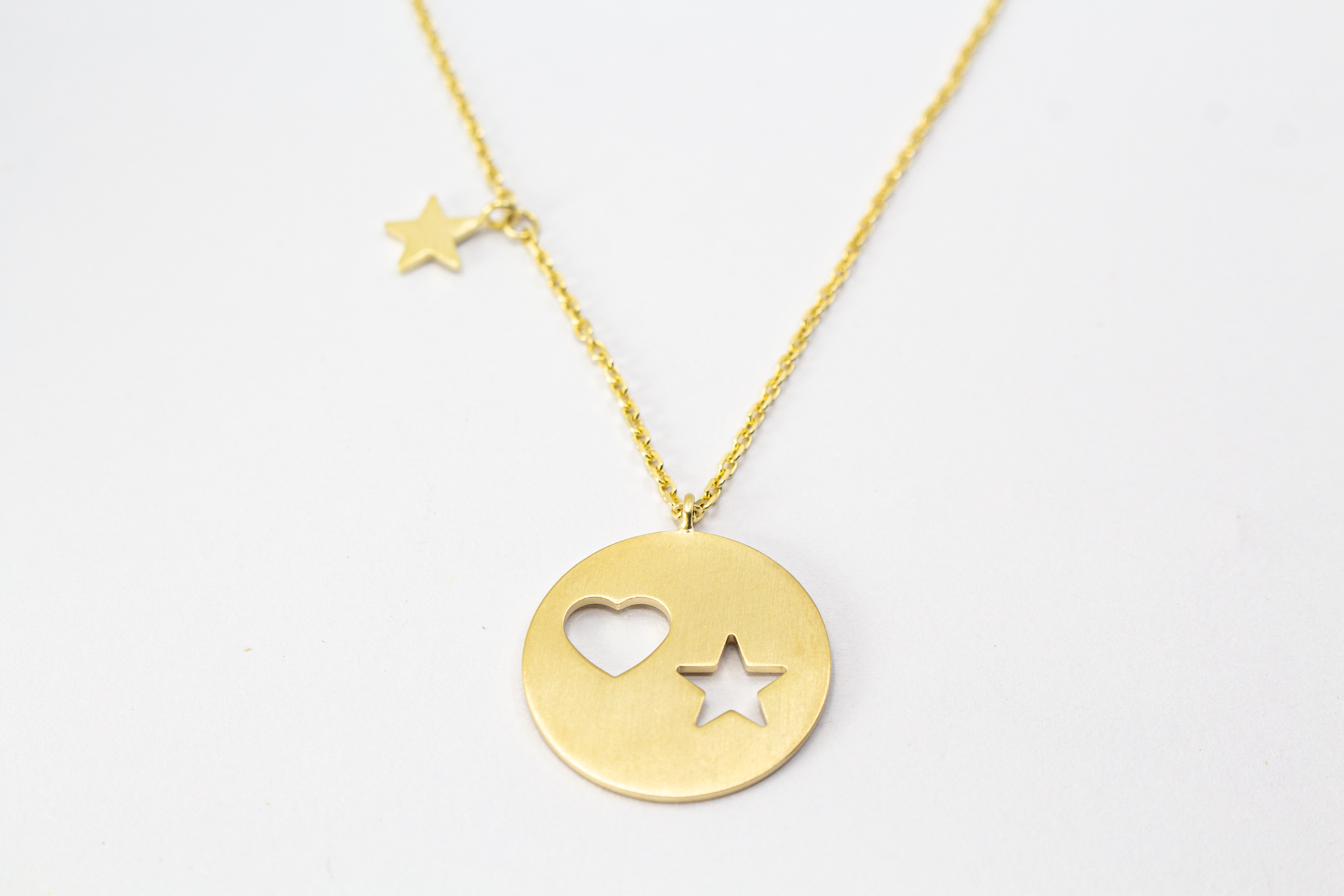 Collier „Sternenliebe“ aus vergoldetem 925er Sterlingsilber mit rundem Anhänger, Herz- und Sternmotiv sowie zusätzlichem Sternanhänger.
