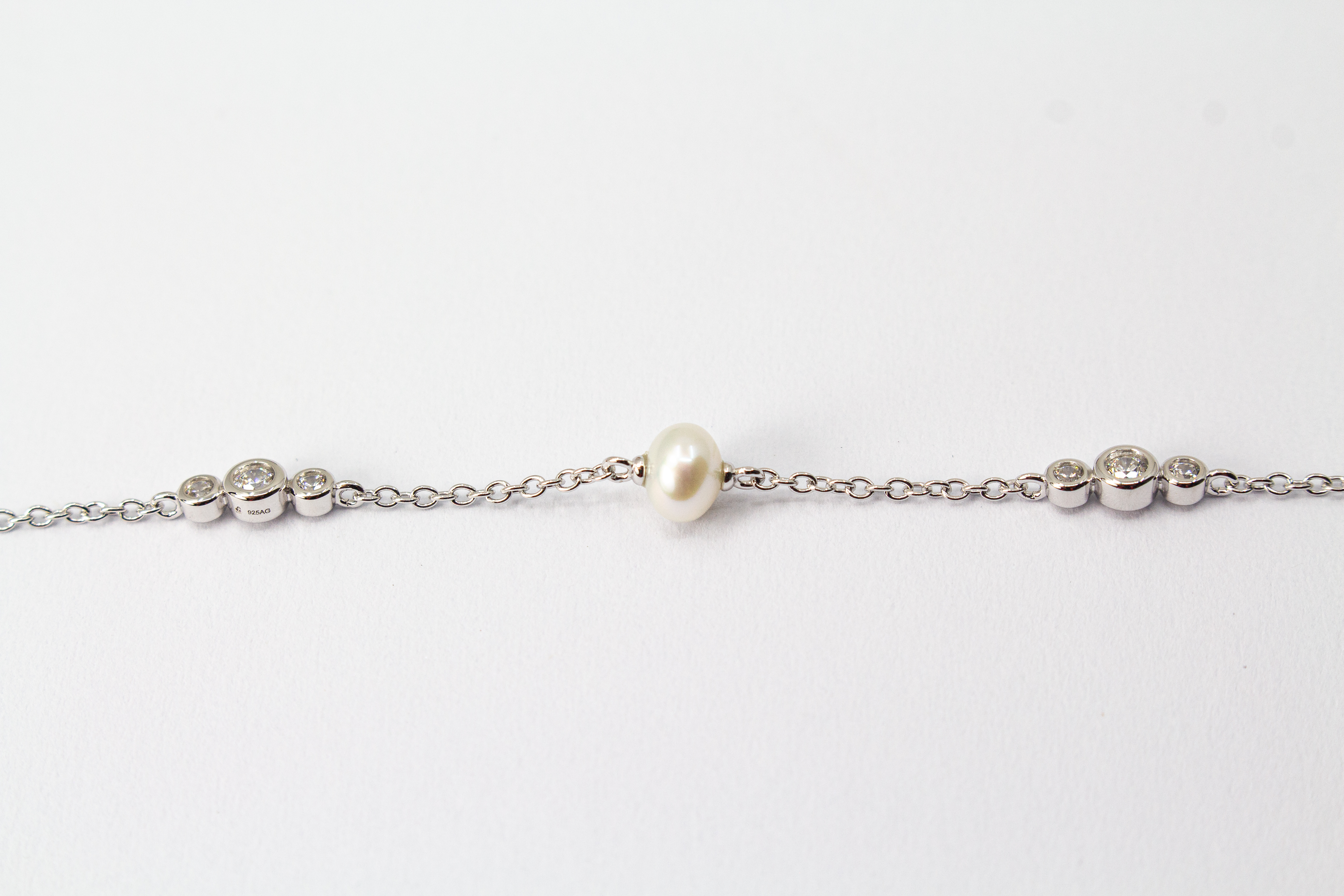 Zartes Armkettchen 'Pearl and Glint' aus rhodiniertem 925er Sterlingsilber mit einer zentralen Süßwasserzuchtperle und seitlichen Zirkonia-Einsätzen,