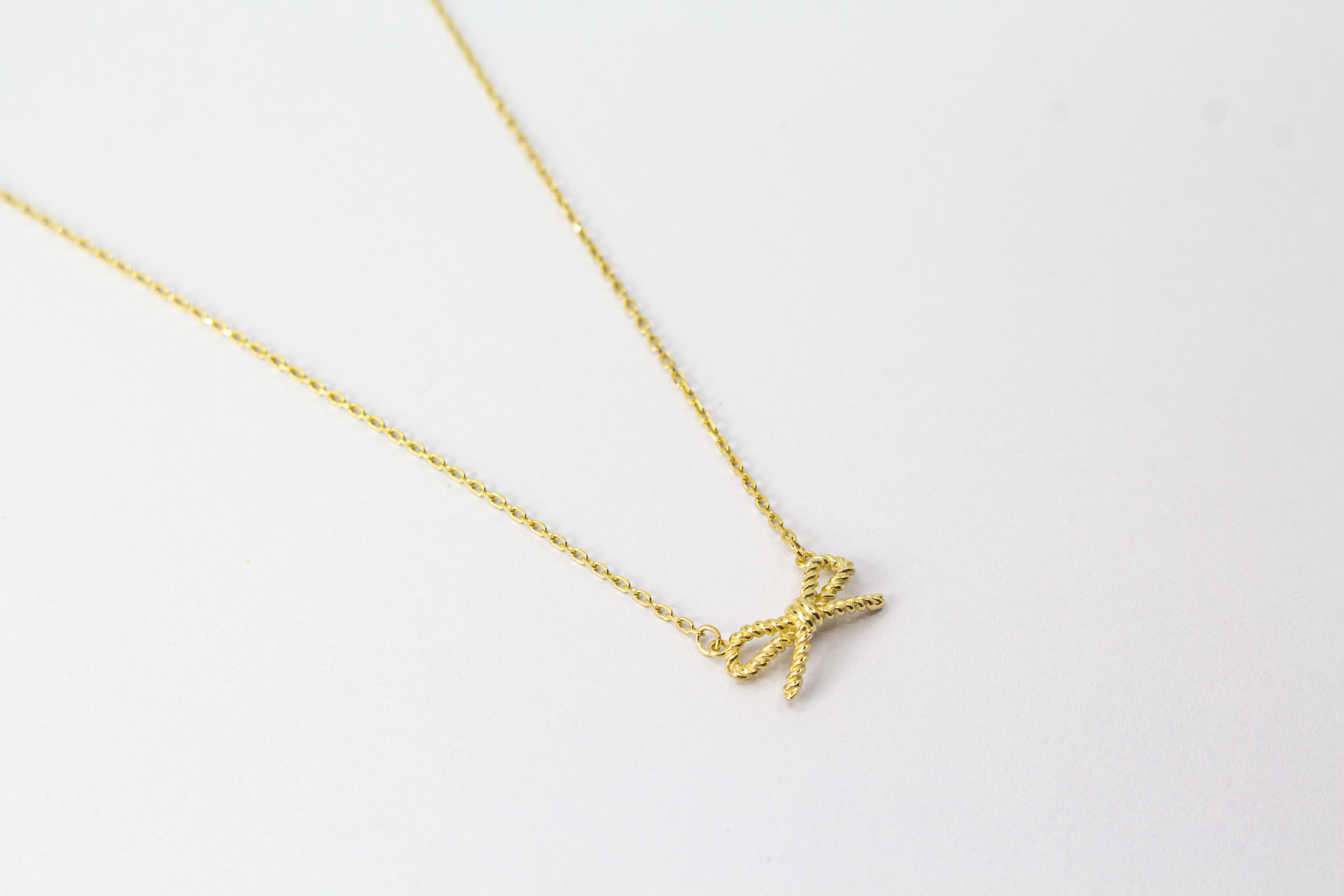 Collier „Schleifenzauber“ aus vergoldetem 925er Sterlingsilber mit filigranem Schleifenanhänger in elegantem, zeitlosem Design.