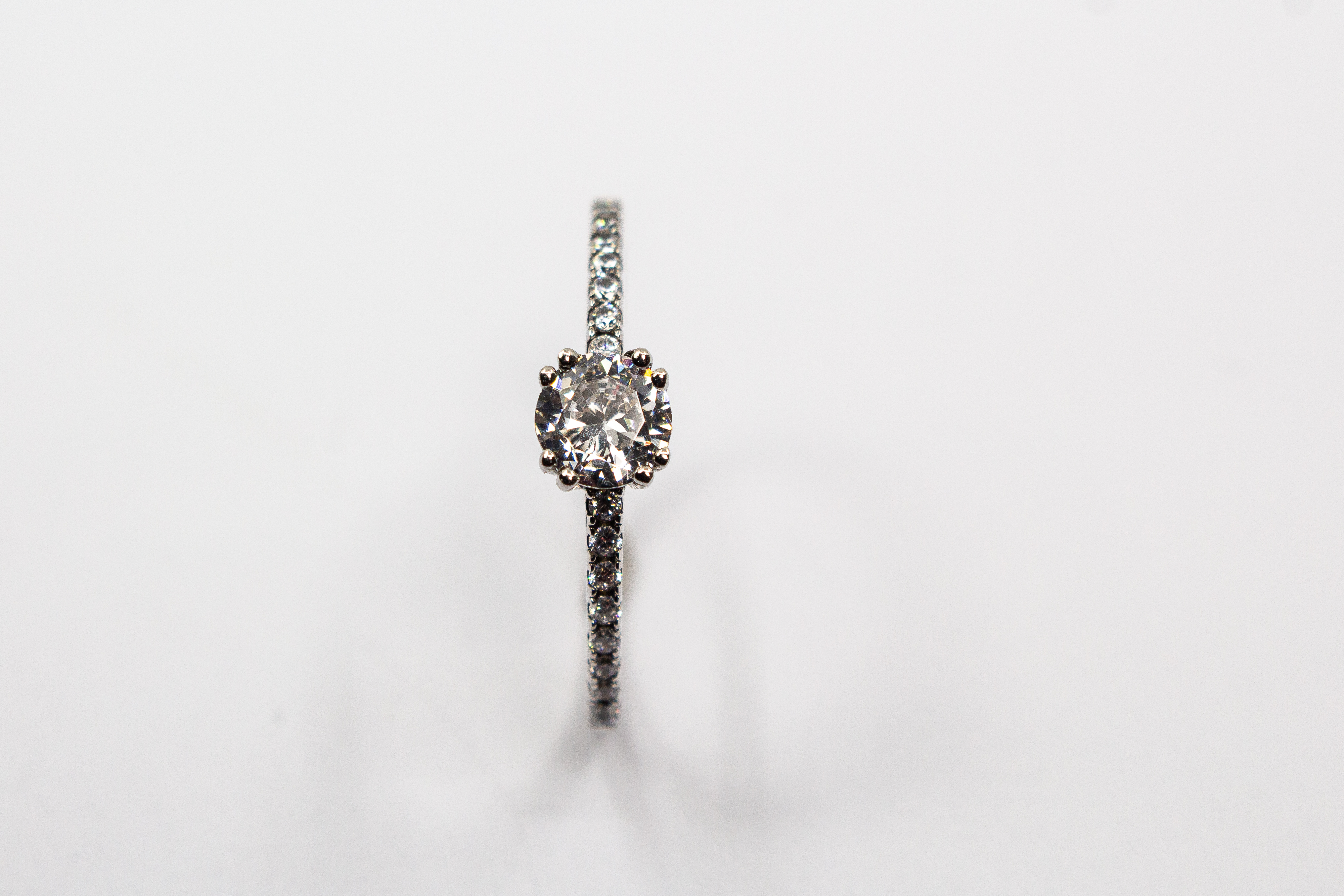 Eleganter Solitärring aus rhodiniertem 925er Silber mit einem großen, in einer Vierer-Krappenfassung gehaltenen Zirkonia und einer mit kleinen Zirkoniasteinen besetzten Ringschiene im Onlineshop von Goldschmiede Regina Kraus.