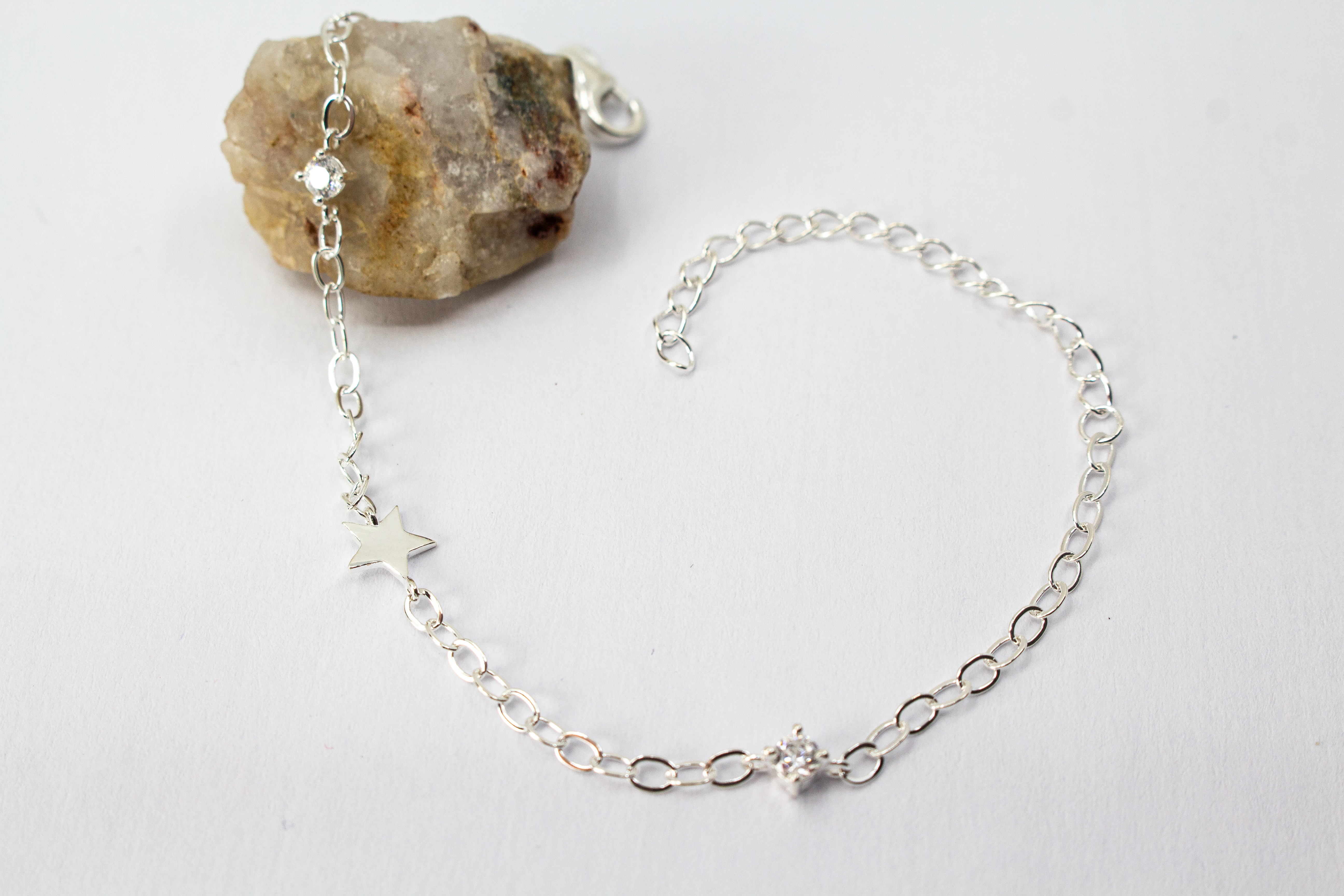 Filigranes Gliederarmband aus hochglanzpoliertem 925er Sterlingsilber mit einem flachen Stern-Anhänger und einem quadratisch gefassten Zirkonia-Kristall.