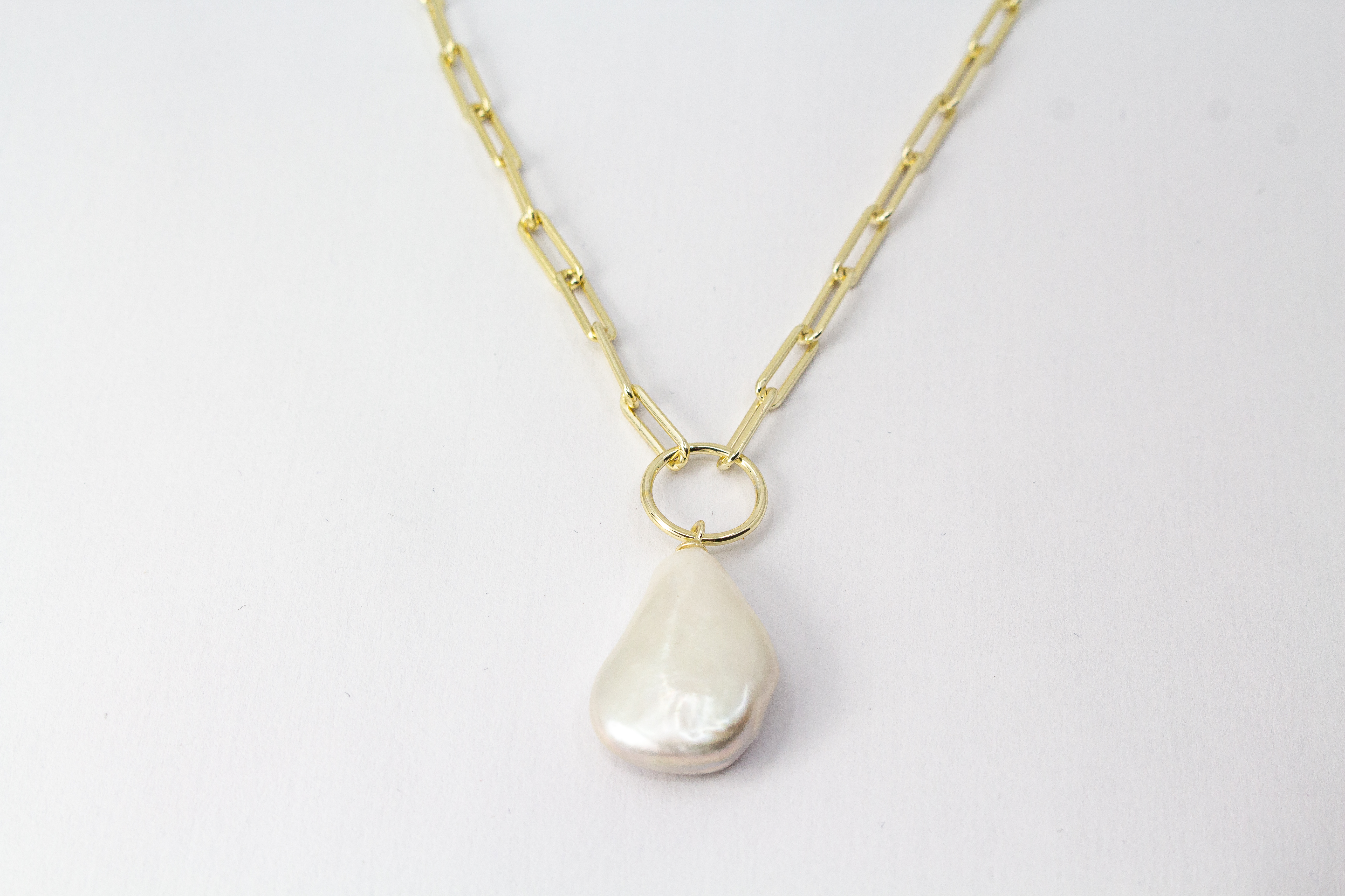 Eine filigrane, hochwertig gelbvergoldete Halskette aus 925er Sterlingsilber von der Goldschmiede Regina Kraus. Als Anhänger dient eine edle, weiße Barock-Zuchtperle mit ihrer typischen, unregelmäßig gewachsenen Form und einem intensiv schimmernden Lüster