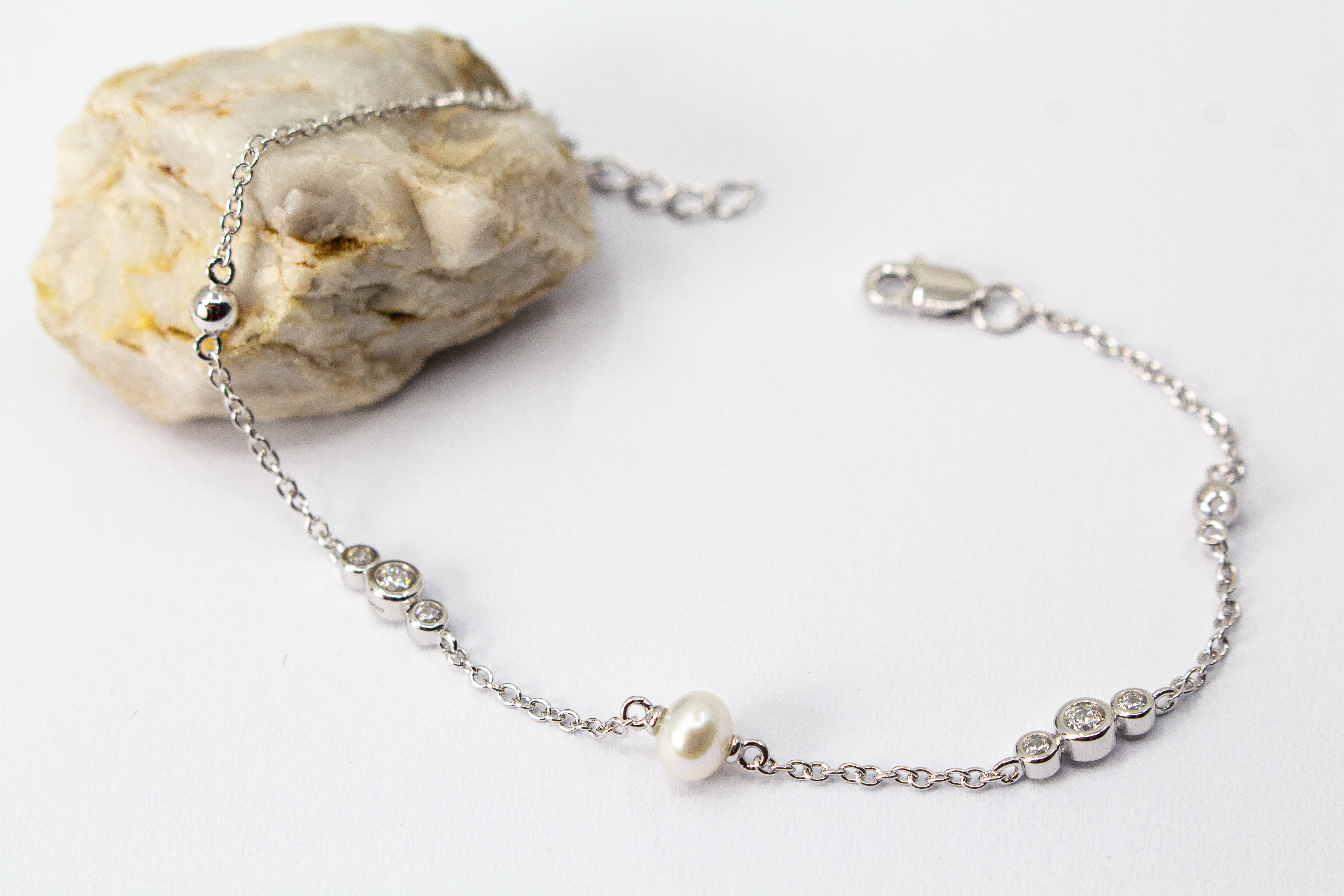 Zartes Armkettchen 'Pearl and Glint' aus rhodiniertem 925er Sterlingsilber mit einer zentralen Süßwasserzuchtperle und seitlichen Zirkonia-Einsätzen,