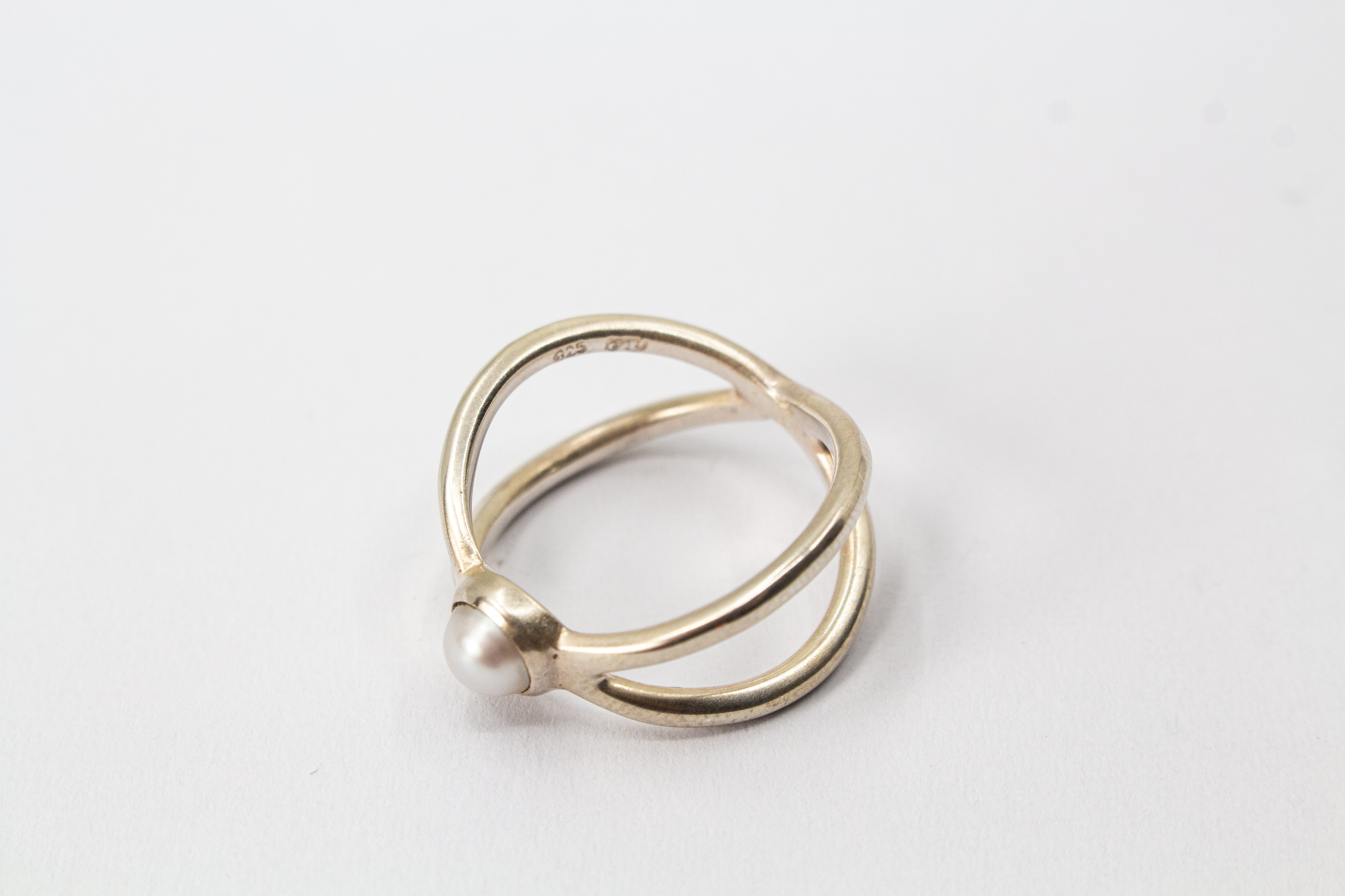 Geschwungener Damenring aus poliertem 925 Sterlingsilber mit einer runden, mittig eingefassten weißen Süßwasserzuchtperle von der Goldschmiede Regina Kraus.