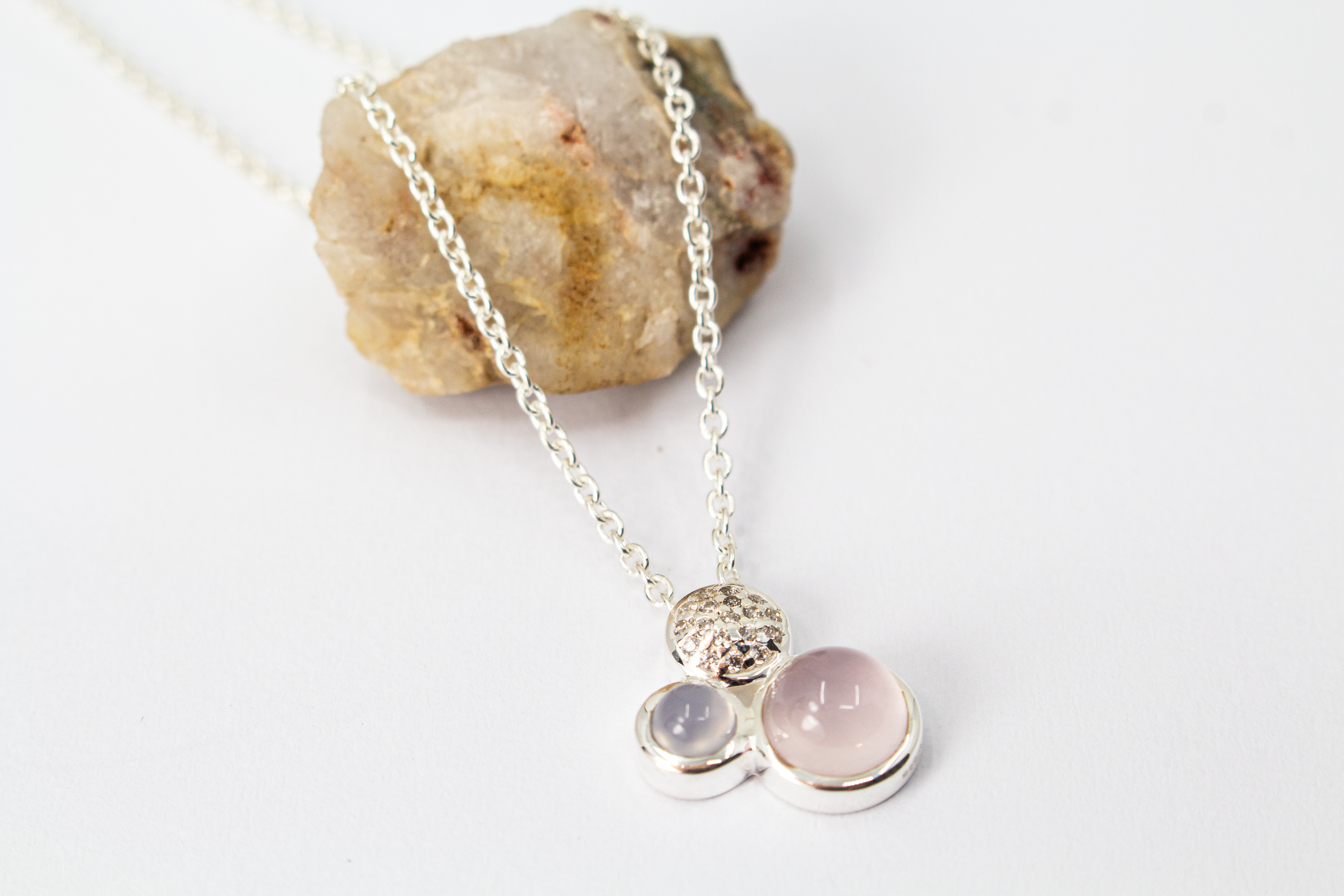 Filigrane Damen-Halskette aus 925er Sterling Silber mit einem dreiteiligen Anhänger, bestehend aus einem runden Rosenquarz-Cabochon in Zartrosa, einem kleineren hellblauen Chalcedon und einem rund gefassten Element mit funkelndem Zirkonia-Besatz