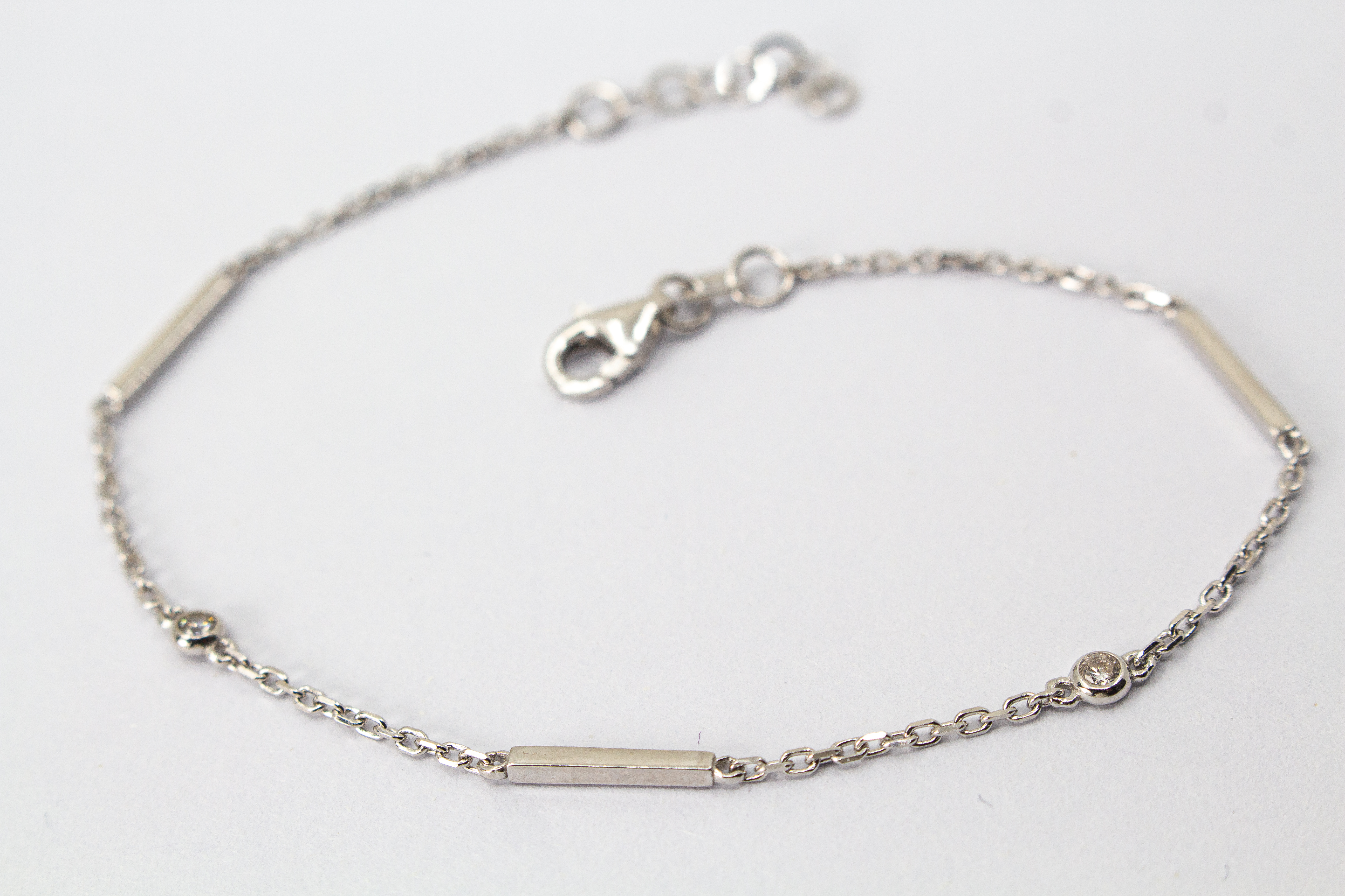 Filigranes, rhodiniertes Damen-Armkettchen aus 925 Sterling Silber mit kleinen, rund gefassten Zirkonia-Steinen und glatten, minimalistischen Stäbchen-Elementen aus dem Online-Shop der Goldschmiede Regina Kraus.