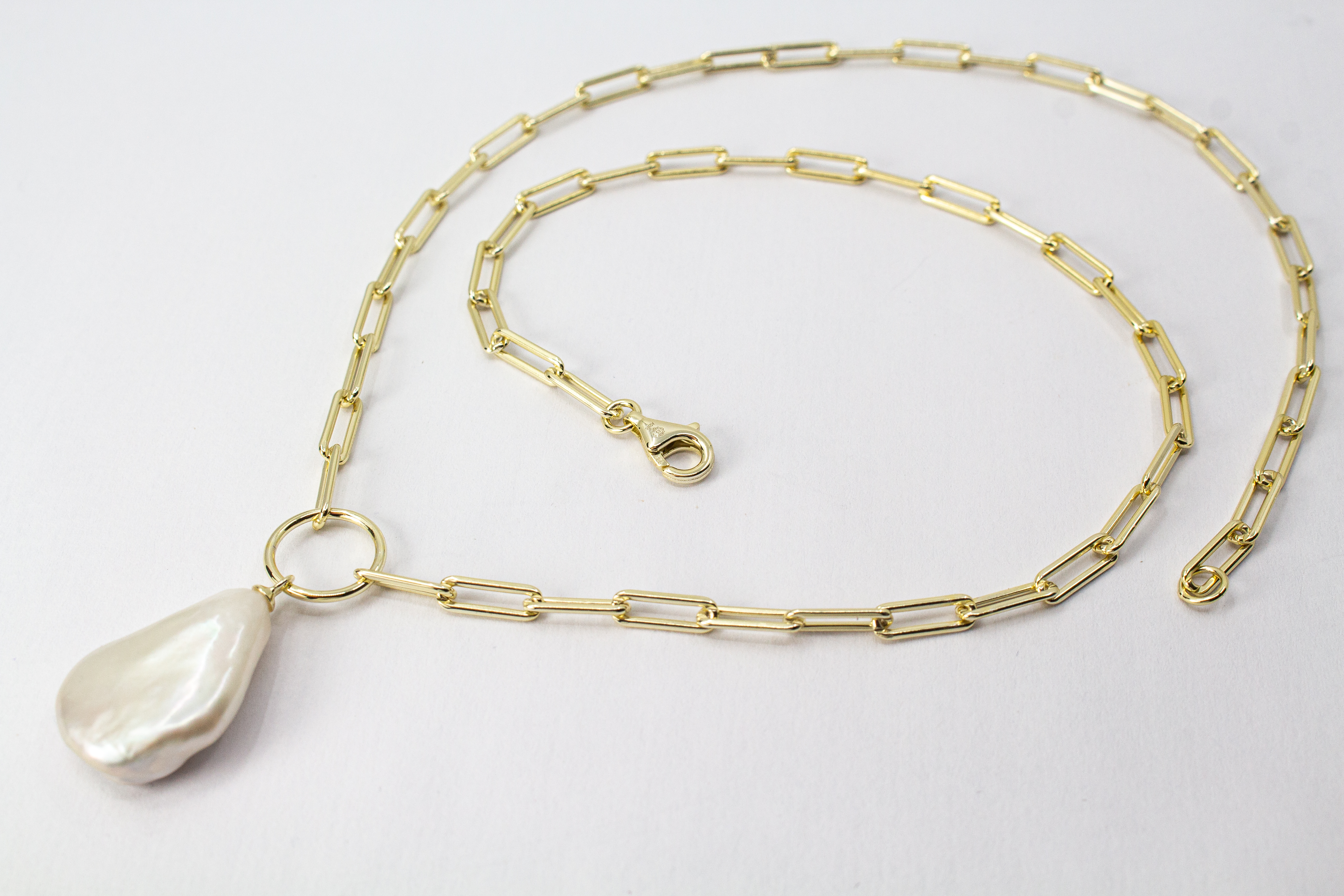 Eine filigrane, hochwertig gelbvergoldete Halskette aus 925er Sterlingsilber von der Goldschmiede Regina Kraus. Als Anhänger dient eine edle, weiße Barock-Zuchtperle mit ihrer typischen, unregelmäßig gewachsenen Form und einem intensiv schimmernden Lüster