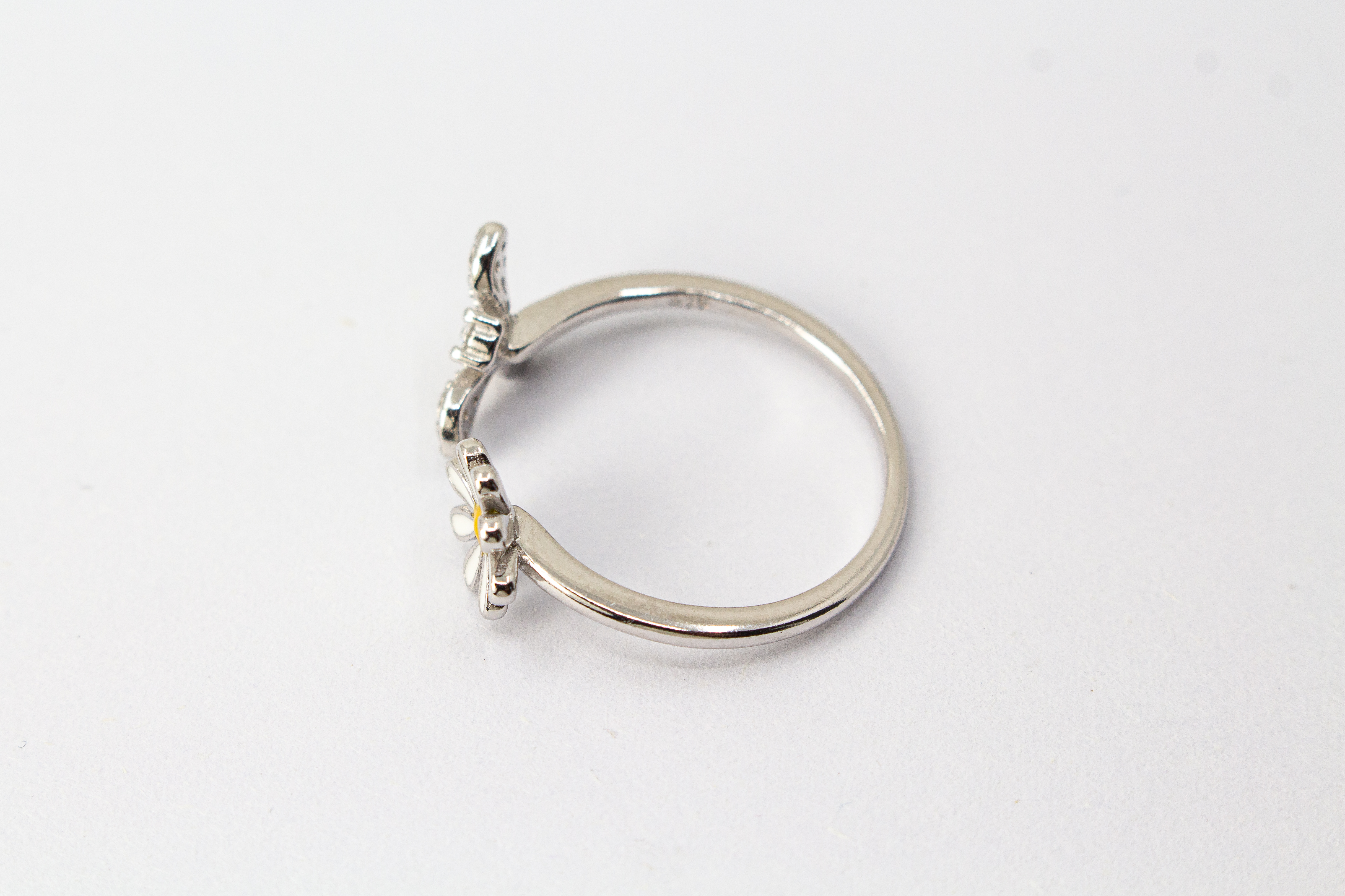 Offener Ring „Blütenbesuch“ aus rhodiniertem 925er Sterlingsilber mit Emaille-Blüte, funkelnder Biene und weißen Zirkonia.