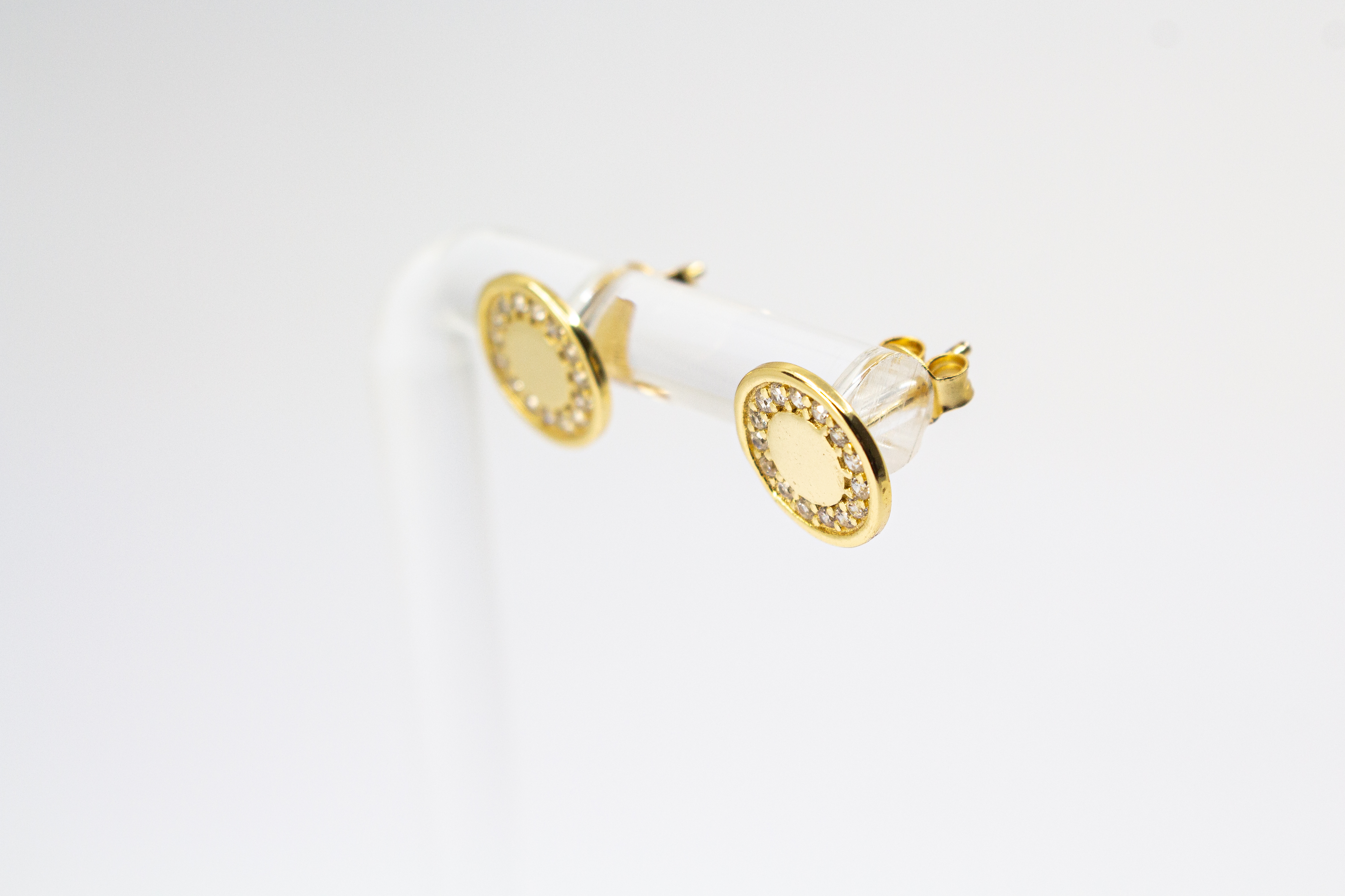 Runde, vergoldete Ohrstecker aus 925er Silber mit einer glatten Innenfläche und einem äußeren Kranz aus funkelnden Zirkoniasteinen im Onlineshop von Goldschmiede Regina Kraus.