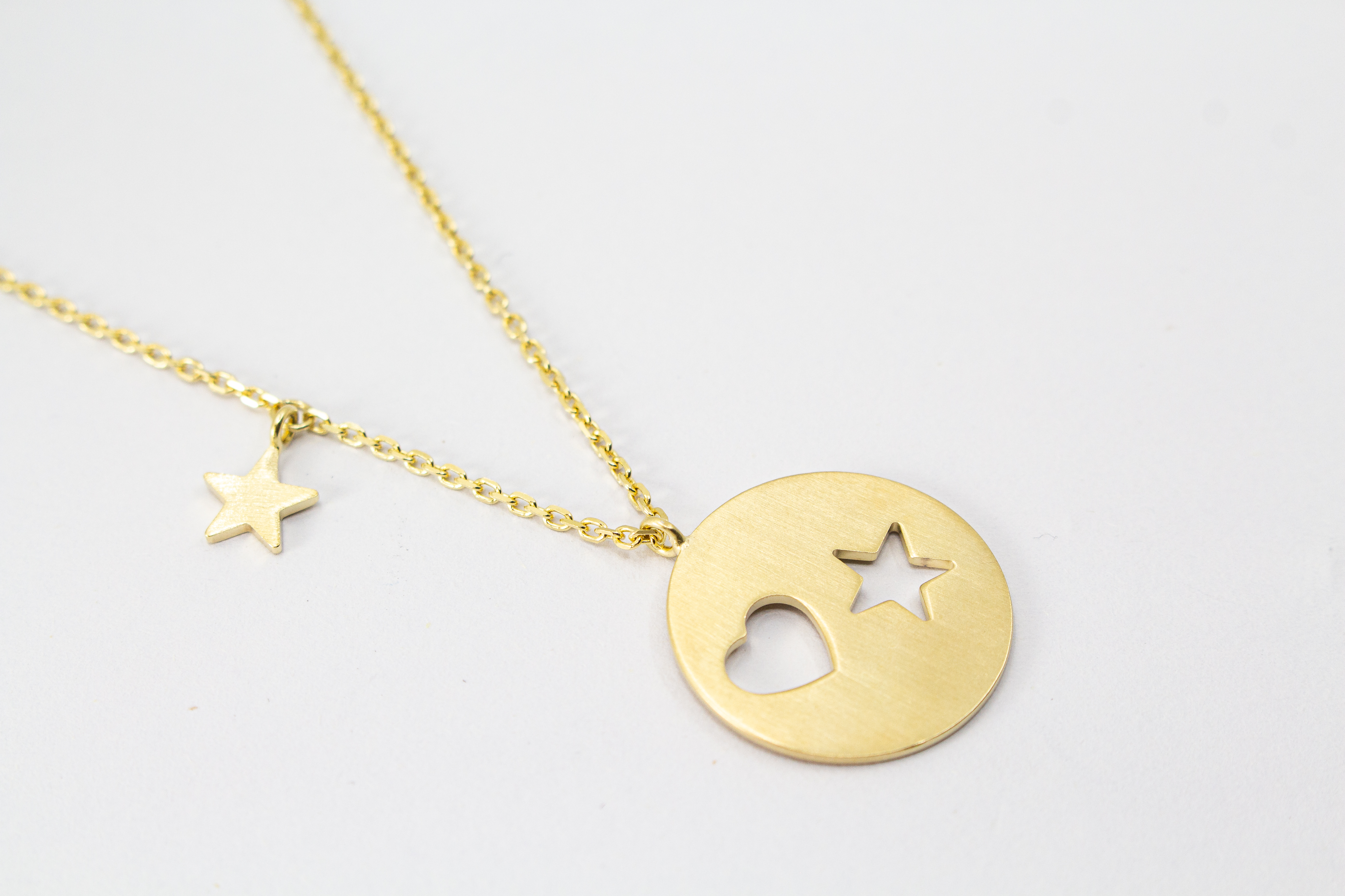 Collier „Sternenliebe“ aus vergoldetem 925er Sterlingsilber mit rundem Anhänger, Herz- und Sternmotiv sowie zusätzlichem Sternanhänger.