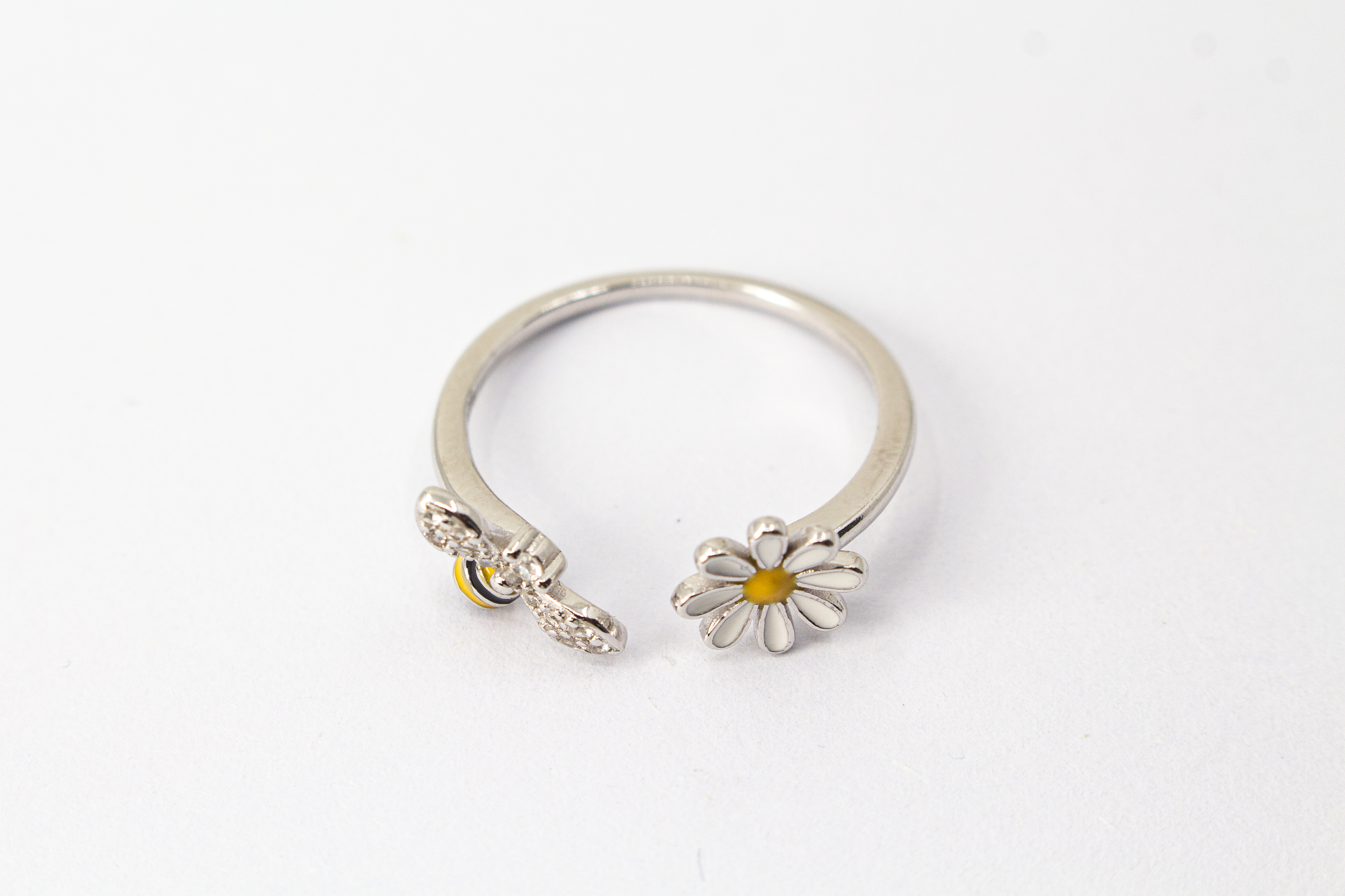 Offener Ring „Blütenbesuch“ aus rhodiniertem 925er Sterlingsilber mit Emaille-Blüte, funkelnder Biene und weißen Zirkonia.