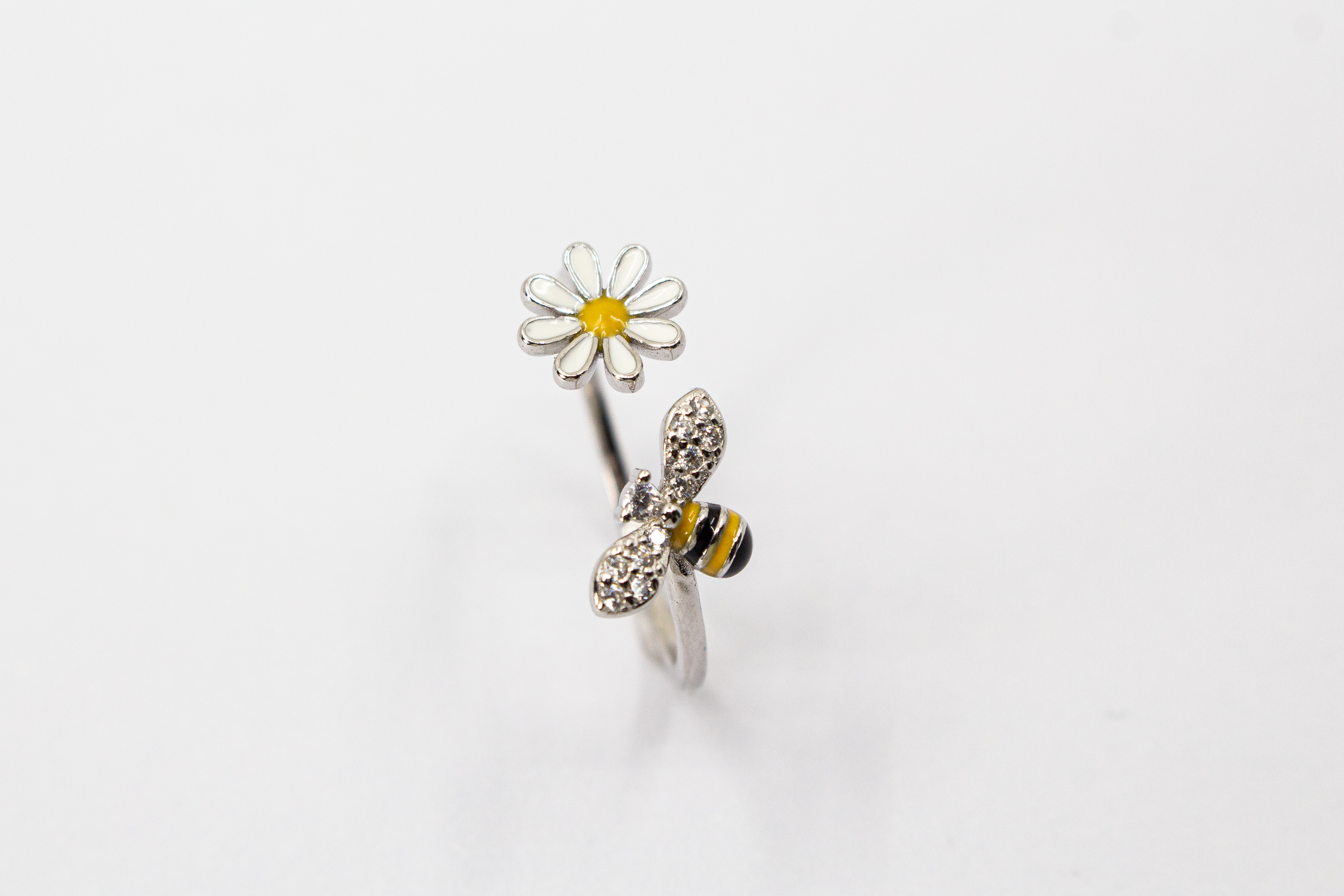 Offener Ring „Blütenbesuch“ aus rhodiniertem 925er Sterlingsilber mit Emaille-Blüte, funkelnder Biene und weißen Zirkonia.