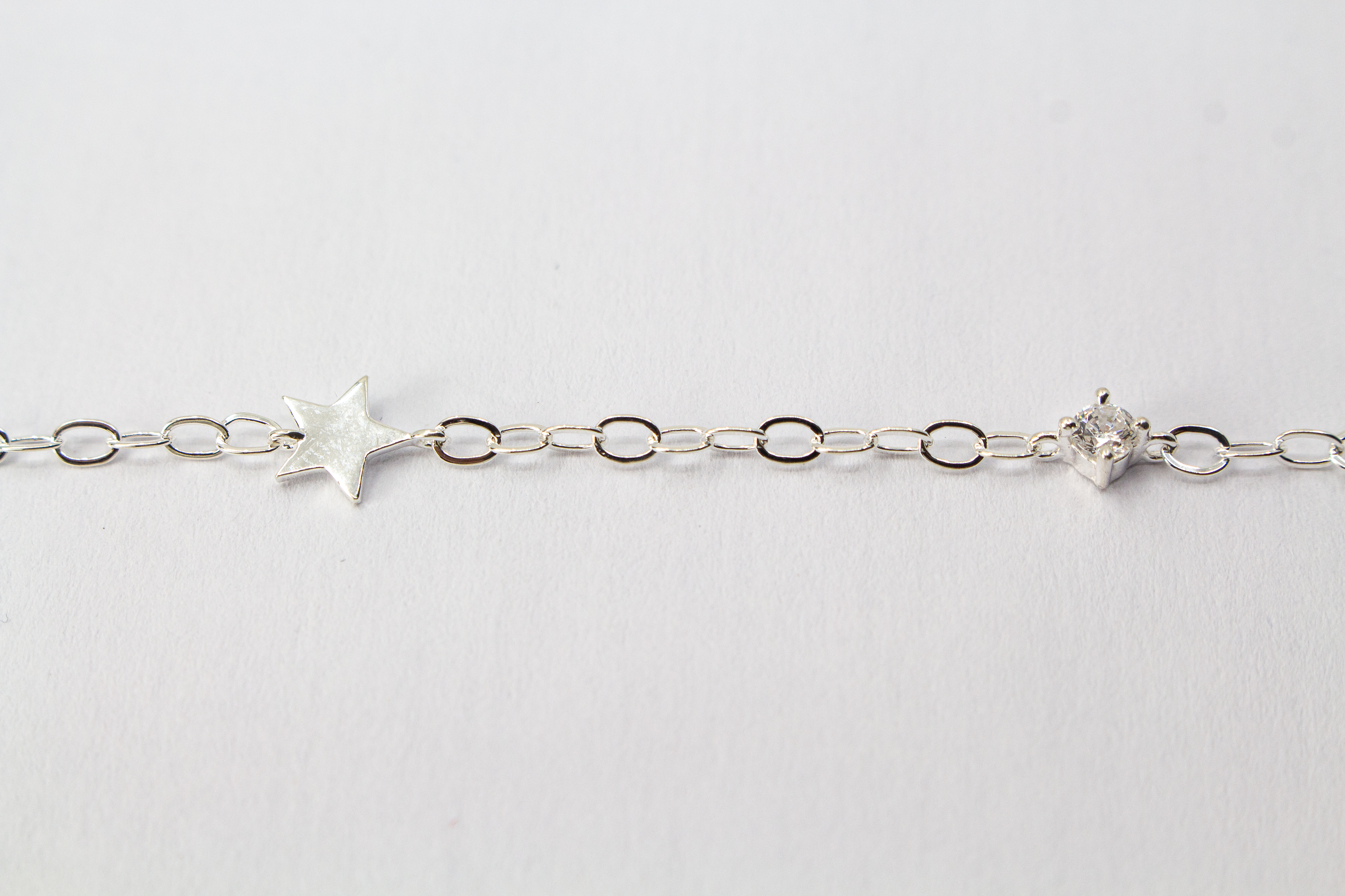 Filigranes Gliederarmband aus hochglanzpoliertem 925er Sterlingsilber mit einem flachen Stern-Anhänger und einem quadratisch gefassten Zirkonia-Kristall.