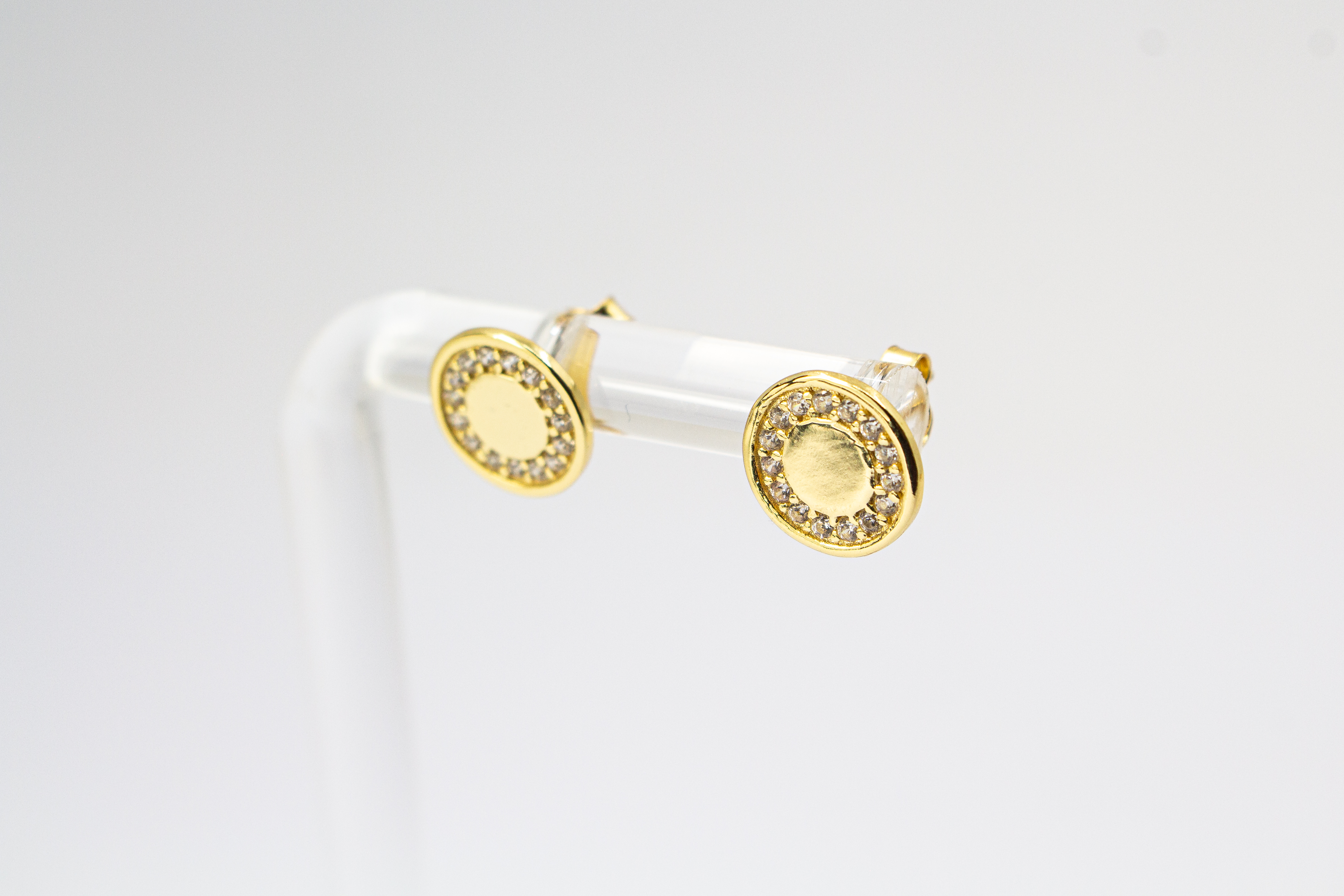 Runde, vergoldete Ohrstecker aus 925er Silber mit einer glatten Innenfläche und einem äußeren Kranz aus funkelnden Zirkoniasteinen im Onlineshop von Goldschmiede Regina Kraus.