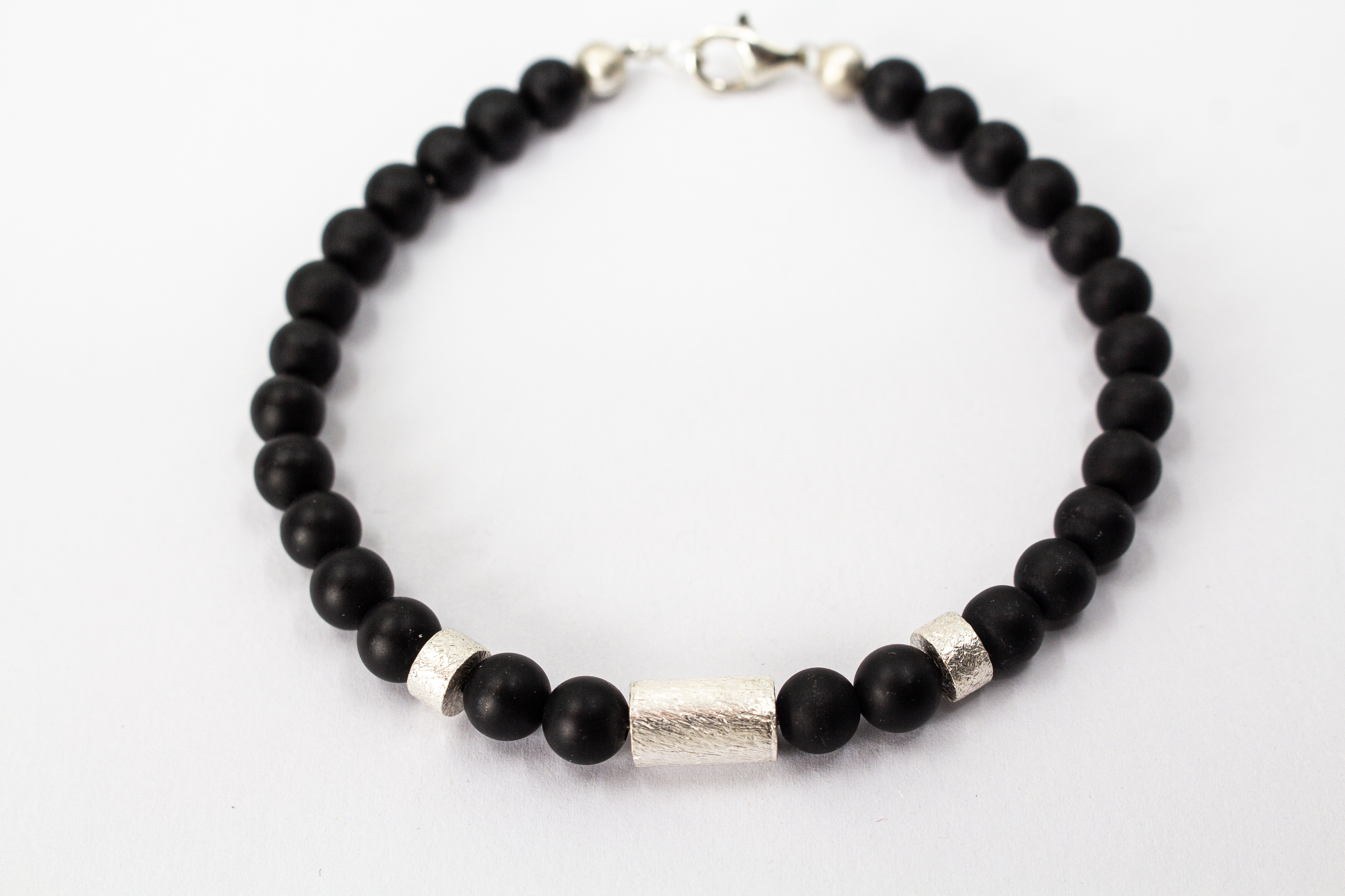 Herrenarmband „Dunkler Pol“ aus mattschwarzem Onyx mit markanten Zwischenteilen aus 925er Sterlingsilber.