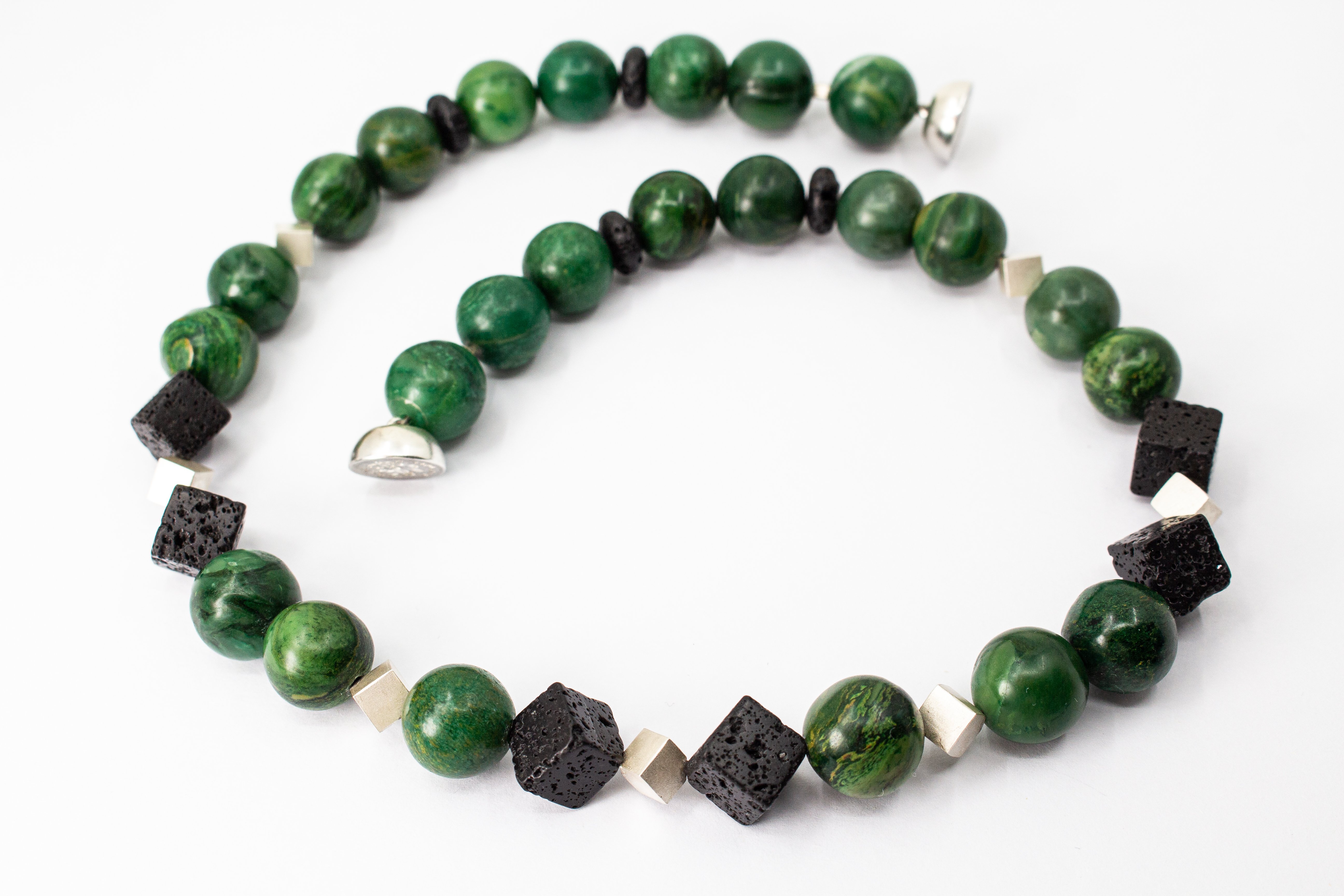 runde, kräftig grüne Prasem-Perlen mit tiefschwarzen, quadratischen Lavastein-Würfeln. Als moderner Akzent sind kleine, matt glänzende Würfelelemente aus 925 Sterlingsilber