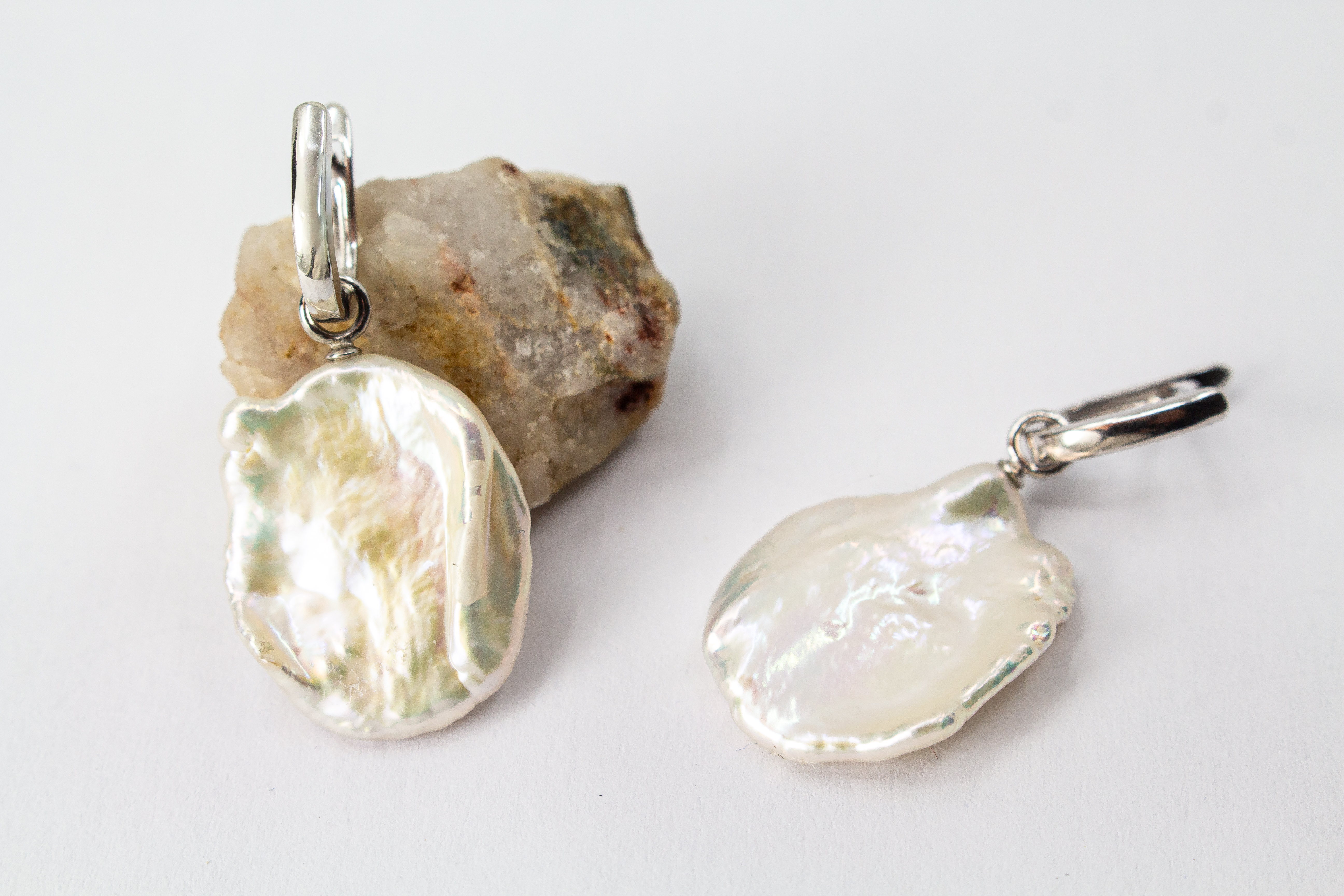 Ein Paar wandelbare Wechselcreolen „Meeresskulptur“ aus rhodiniertem 925er Sterlingsilber von der Goldschmiede Regina Kraus. Die Ohrringe tragen abnehmbare Anhänger aus großen, flachen weißen Keshi-Zuchtperlen, die durch ihre organische Freiform wie eine