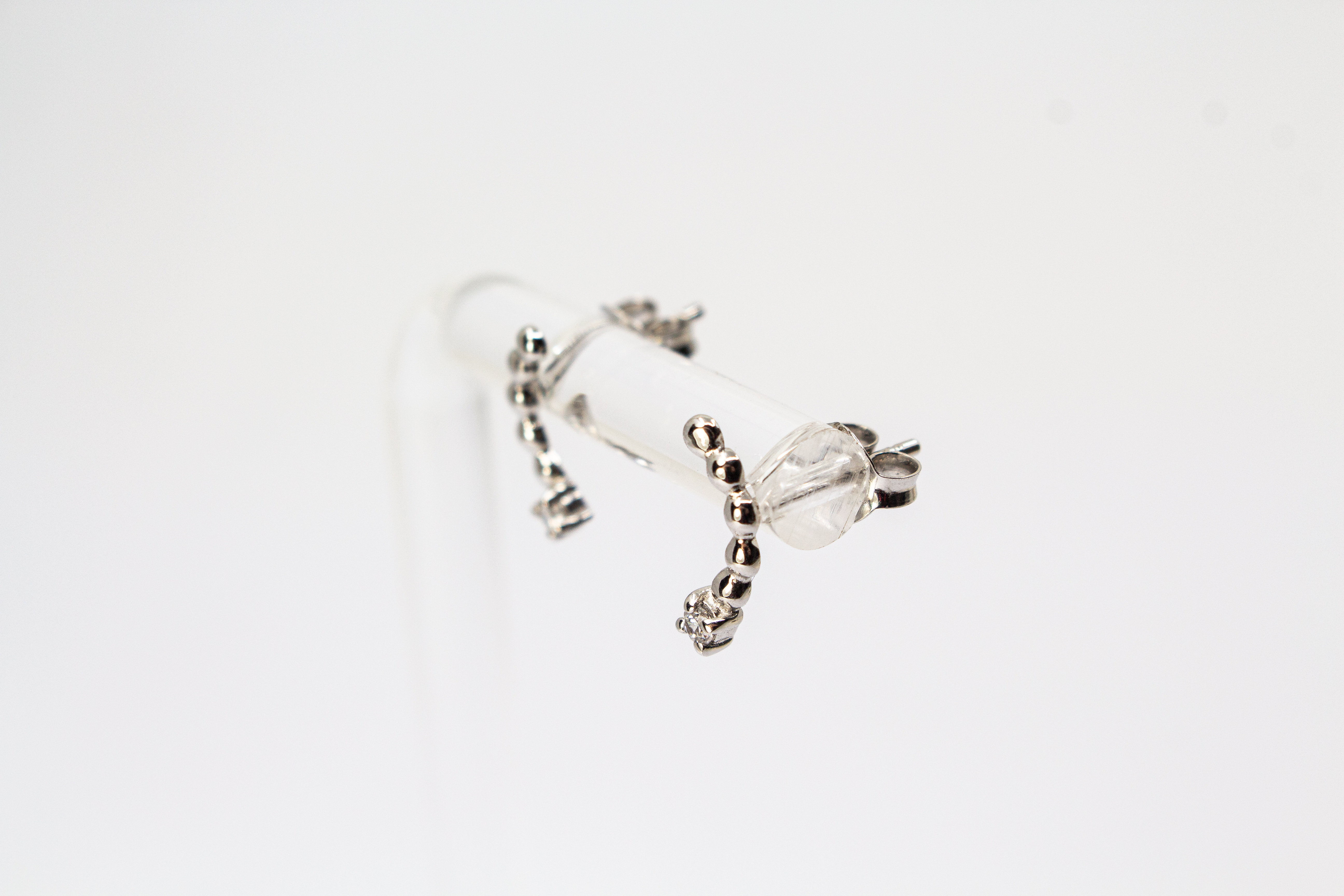 Moderne Ohrstecker aus rhodiniertem 925er Silber mit einem geschwungenen Bogen aus feinen Silberkugeln und funkelnden Zirkoniasteinen im Onlineshop von Goldschmiede Regina Kraus.