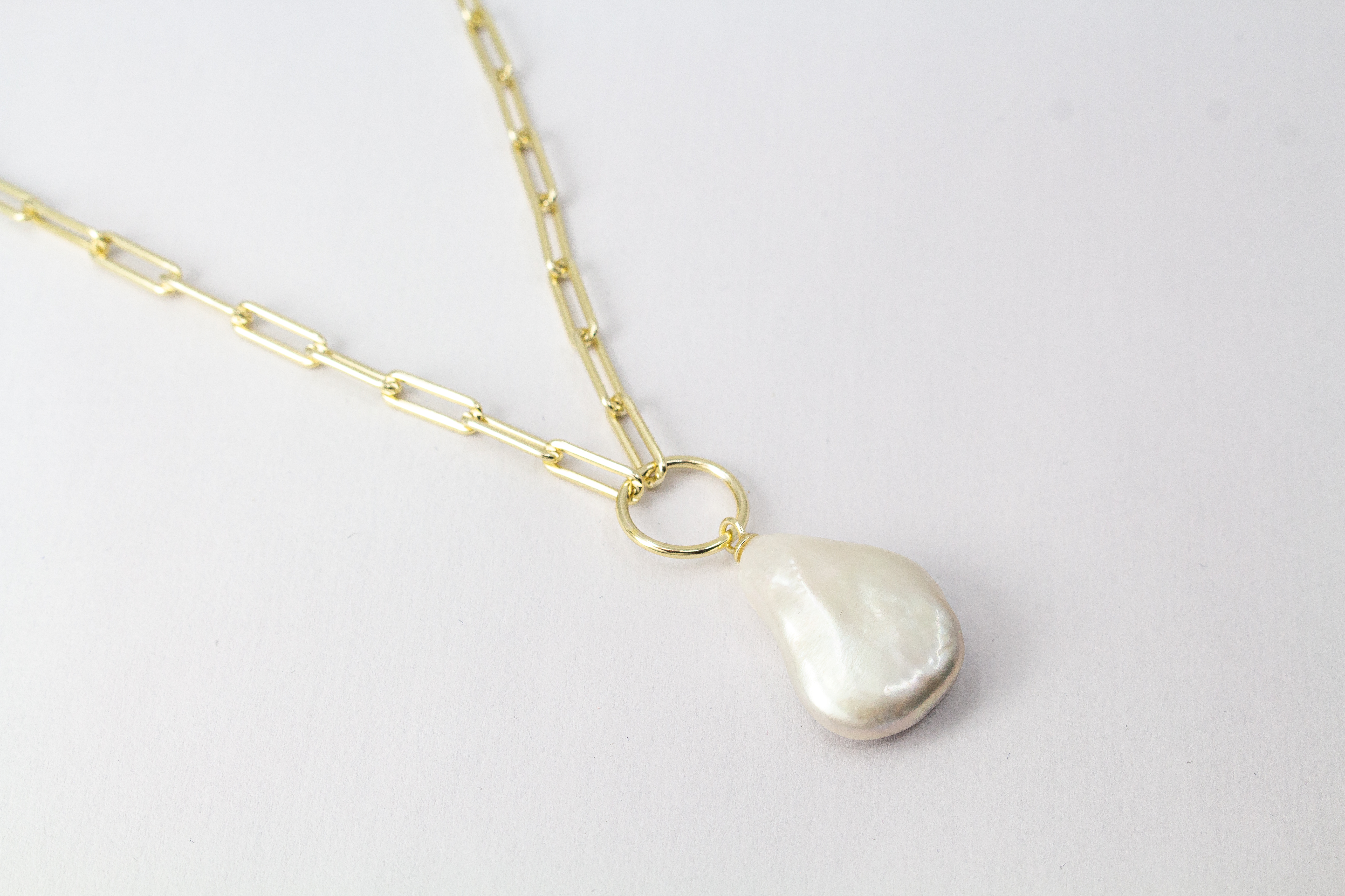Eine filigrane, hochwertig gelbvergoldete Halskette aus 925er Sterlingsilber von der Goldschmiede Regina Kraus. Als Anhänger dient eine edle, weiße Barock-Zuchtperle mit ihrer typischen, unregelmäßig gewachsenen Form und einem intensiv schimmernden Lüster