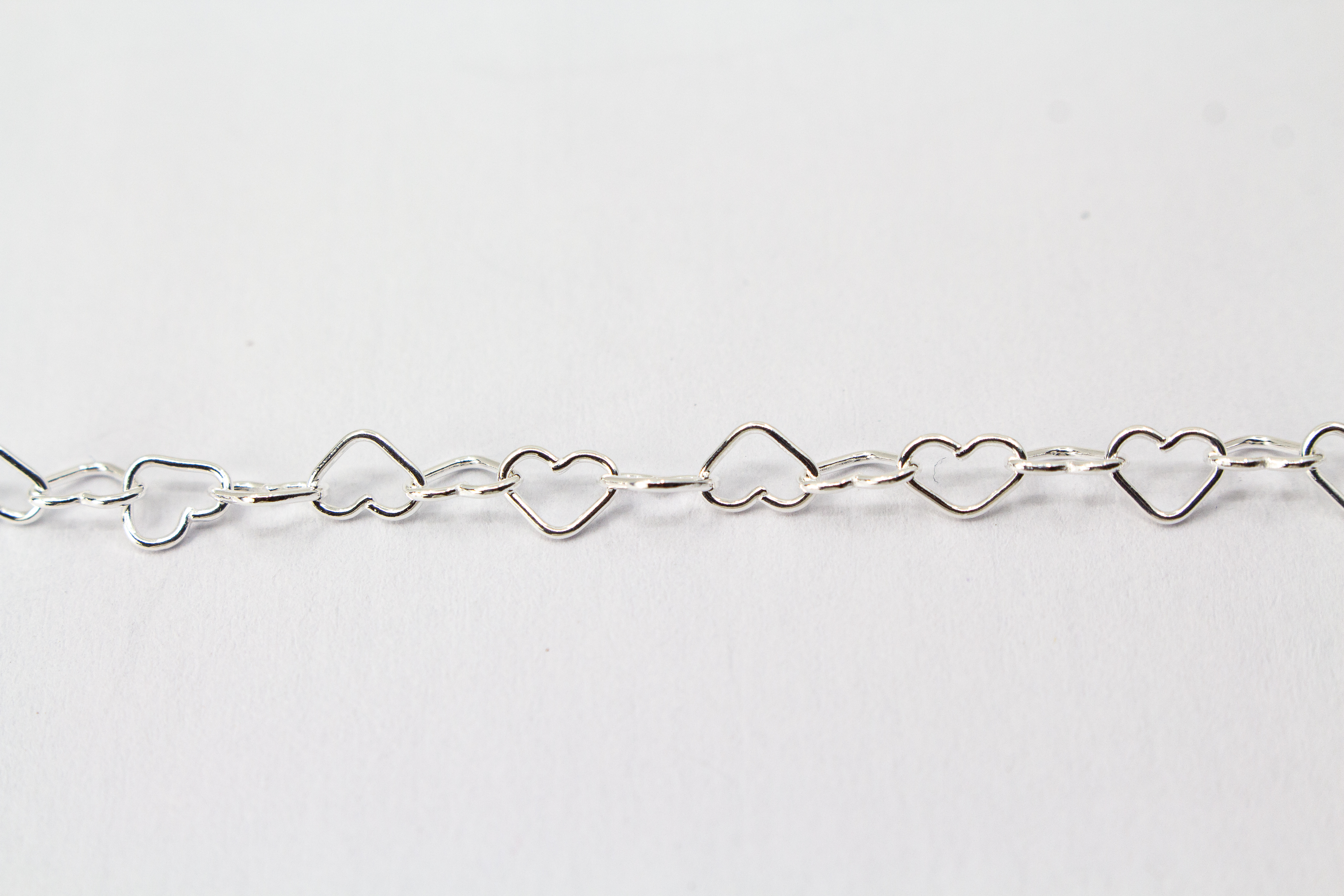 Zarte Halskette „Herz an Herz“ aus 925er Sterlingsilber, gefertigt aus einer Reihe kleiner, miteinander verbundener offener Herzen aus dem Onlineshop der Goldschmiede Regina Kraus.