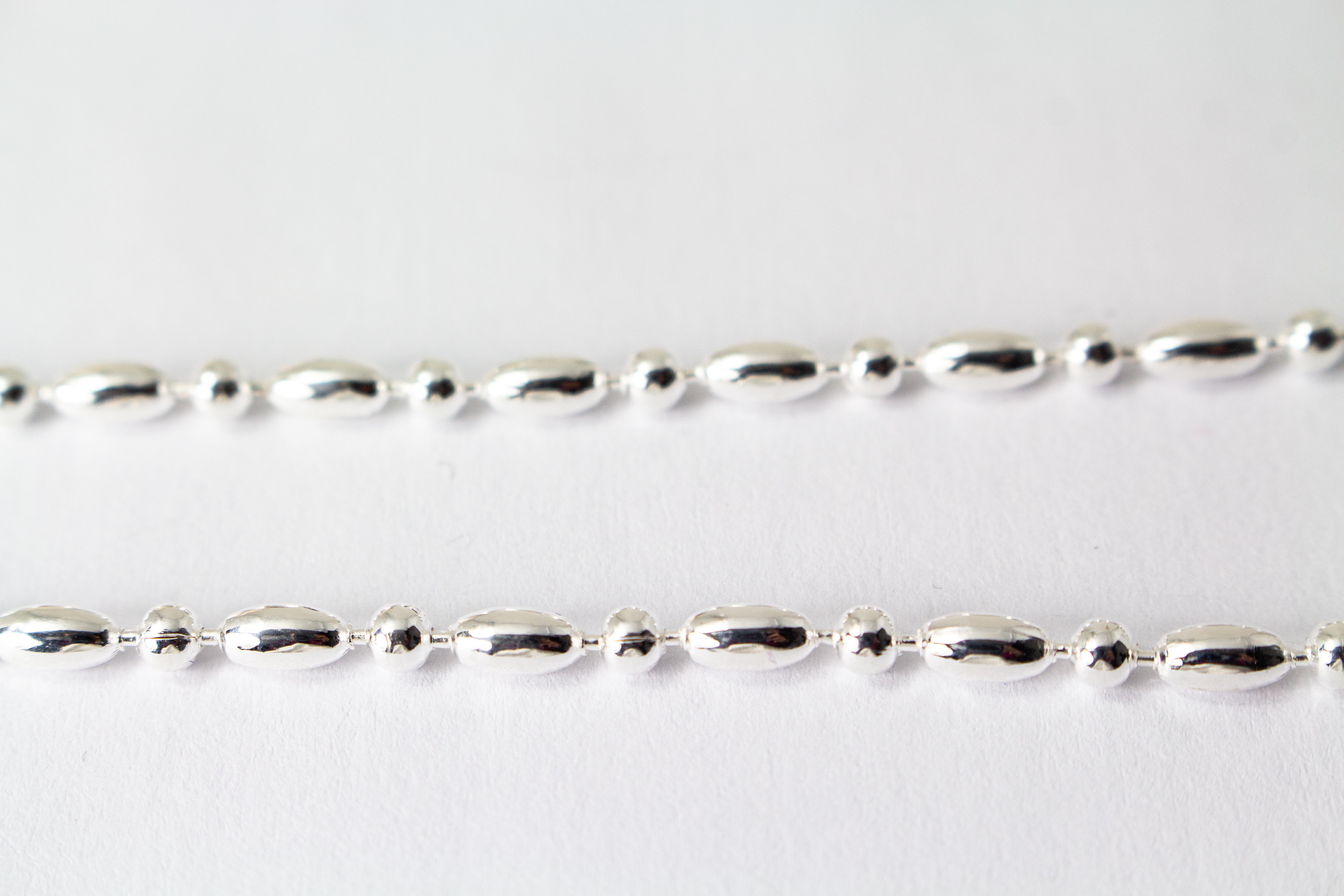 Filigrane Silberkette aus hochglanzpoliertem 925er Sterlingsilber mit einem rhythmischen Wechsel aus Oliven- und Kugel-Elementen auf hellem Untergrund, exklusiv erhältlich im Schmuck-Onlineshop der Goldschmiede Regina Kraus.