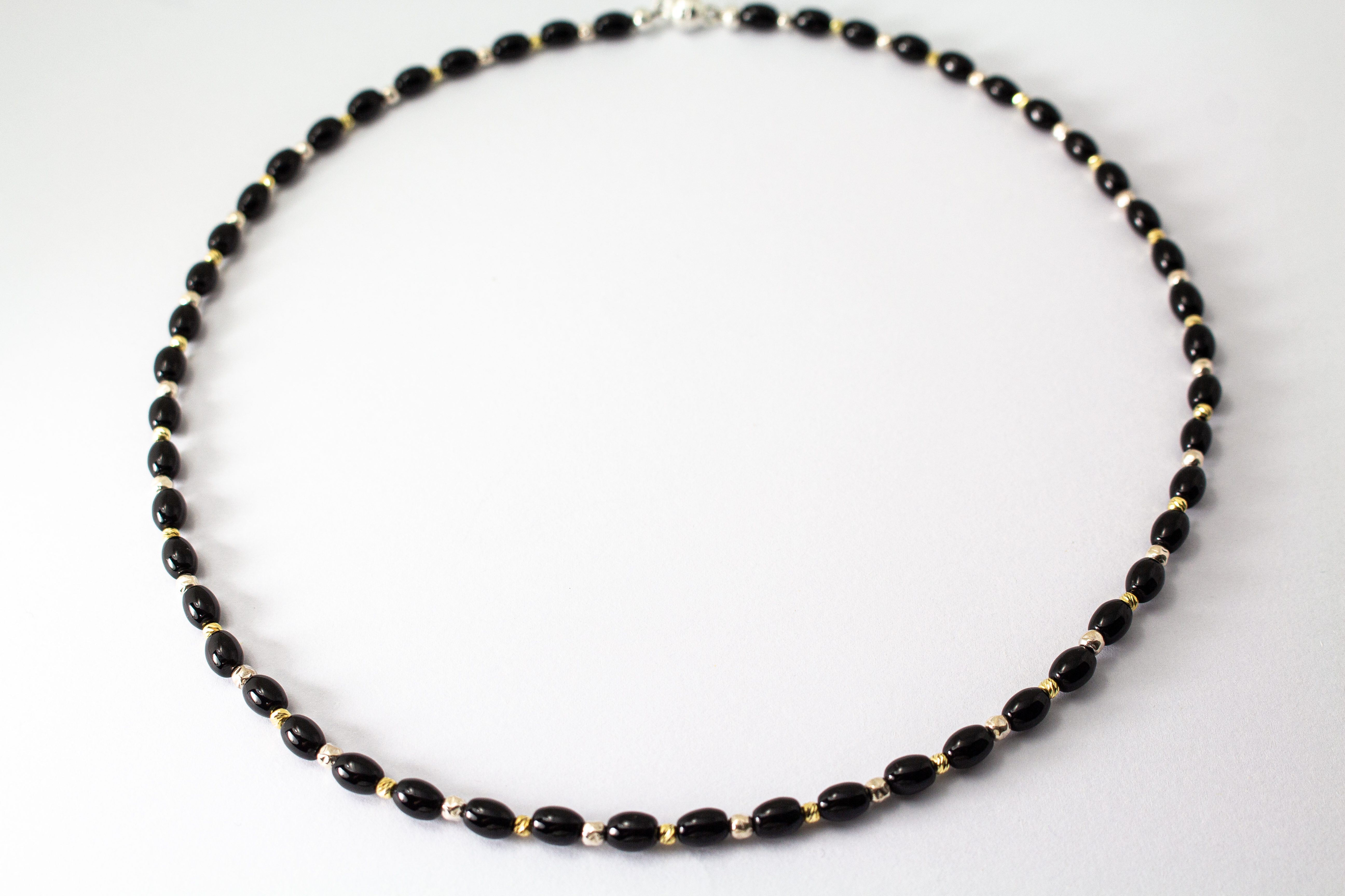 Elegante Onyx Kette „Mitternachtsglanz“ mit schwarzen Onyx-Perlen, Zwischenteilen aus 925er Sterlingsilber und vergoldeten Silberdetails.